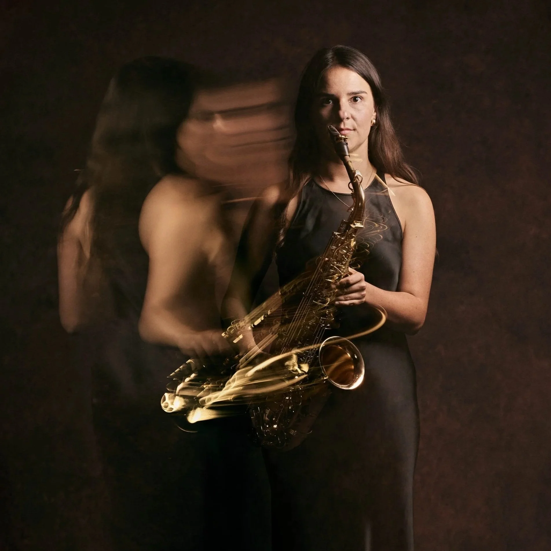 A woman holding a saxophone while standing in front of a dark background, with a motion blur effect on her and the instrument.