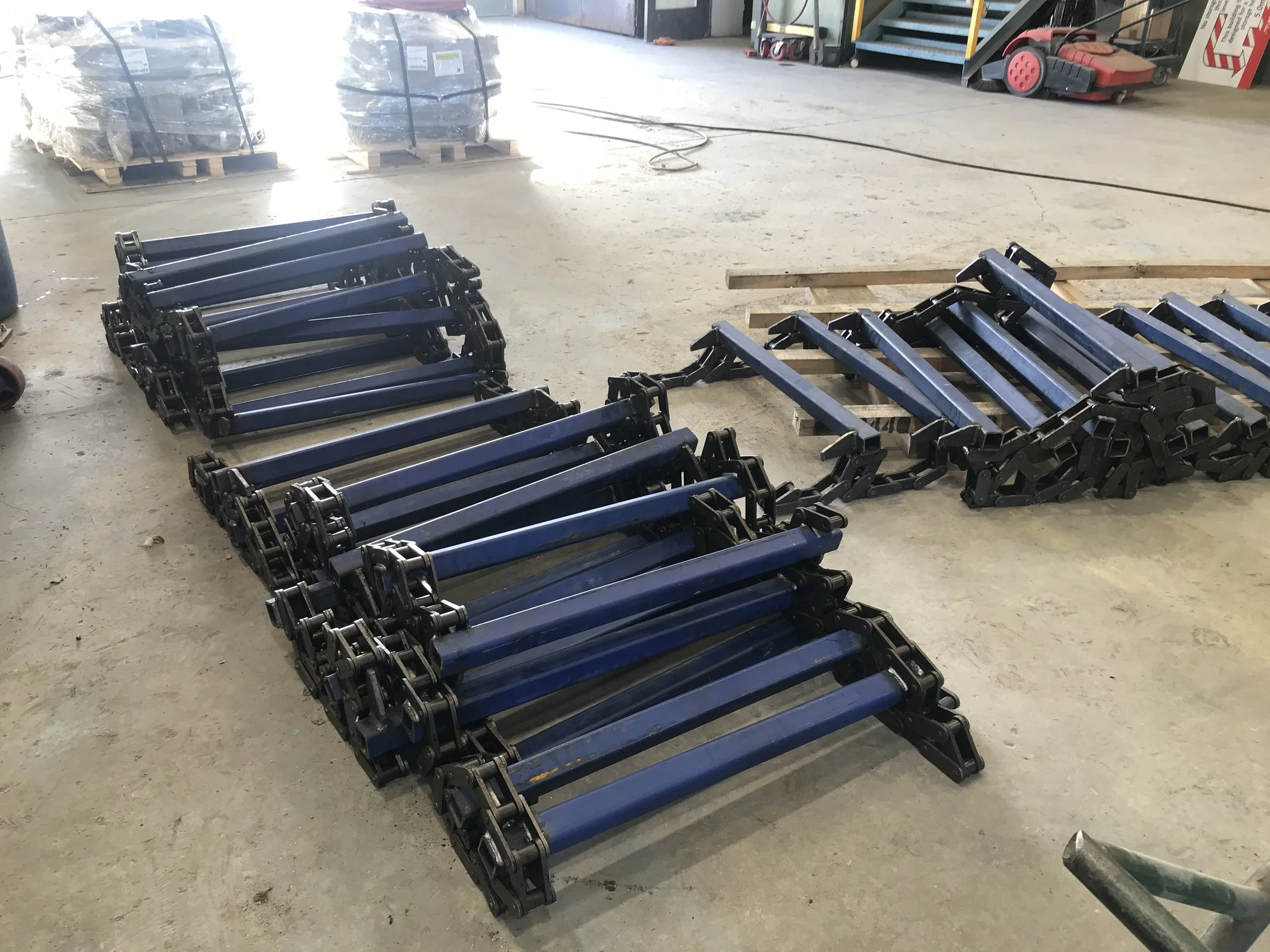 Blue ladder sections stacked on the floor in an industrial or warehouse setting.