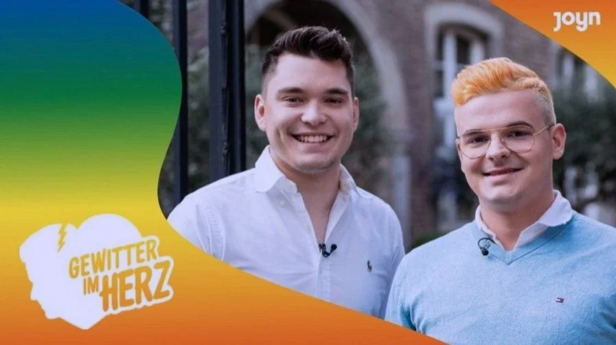 Jan Zimmermann and Tim Lehmann from YouTube channel Gewitter im Kopf
 standing outdoors on a street with historic buildings, in front of a colorful graphic background with the text 'Gewitter im Herz' and the logo 'Joyn' in the top right corner.