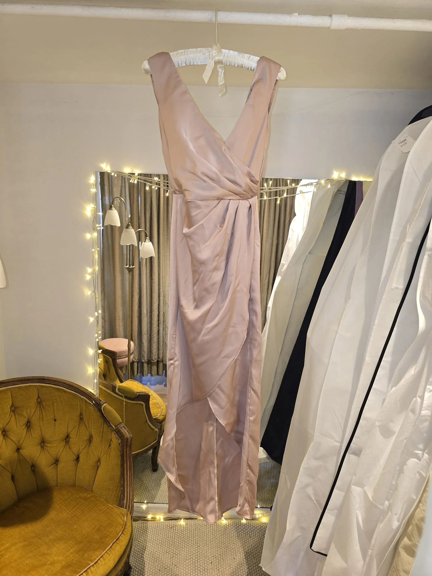 Blush pink satin wrap bridesmaid dress with a draped waist and V-neckline, shown before tailoring at Brighton Alterations for custom fit adjustments.