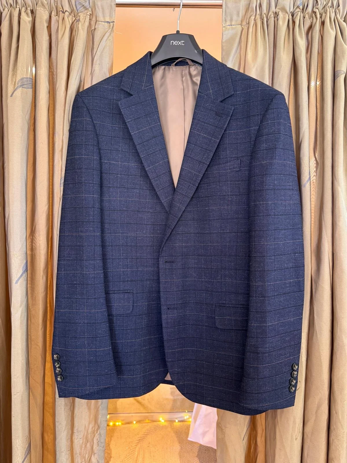 A navy wool-blend check blazer with structured shoulders and windowpane detailing, shown pinned and ready for tailoring. This "before" shot captures the garment in its pre-alteration stage—perfect for weddings, businesswear, or smart-casual looks.
