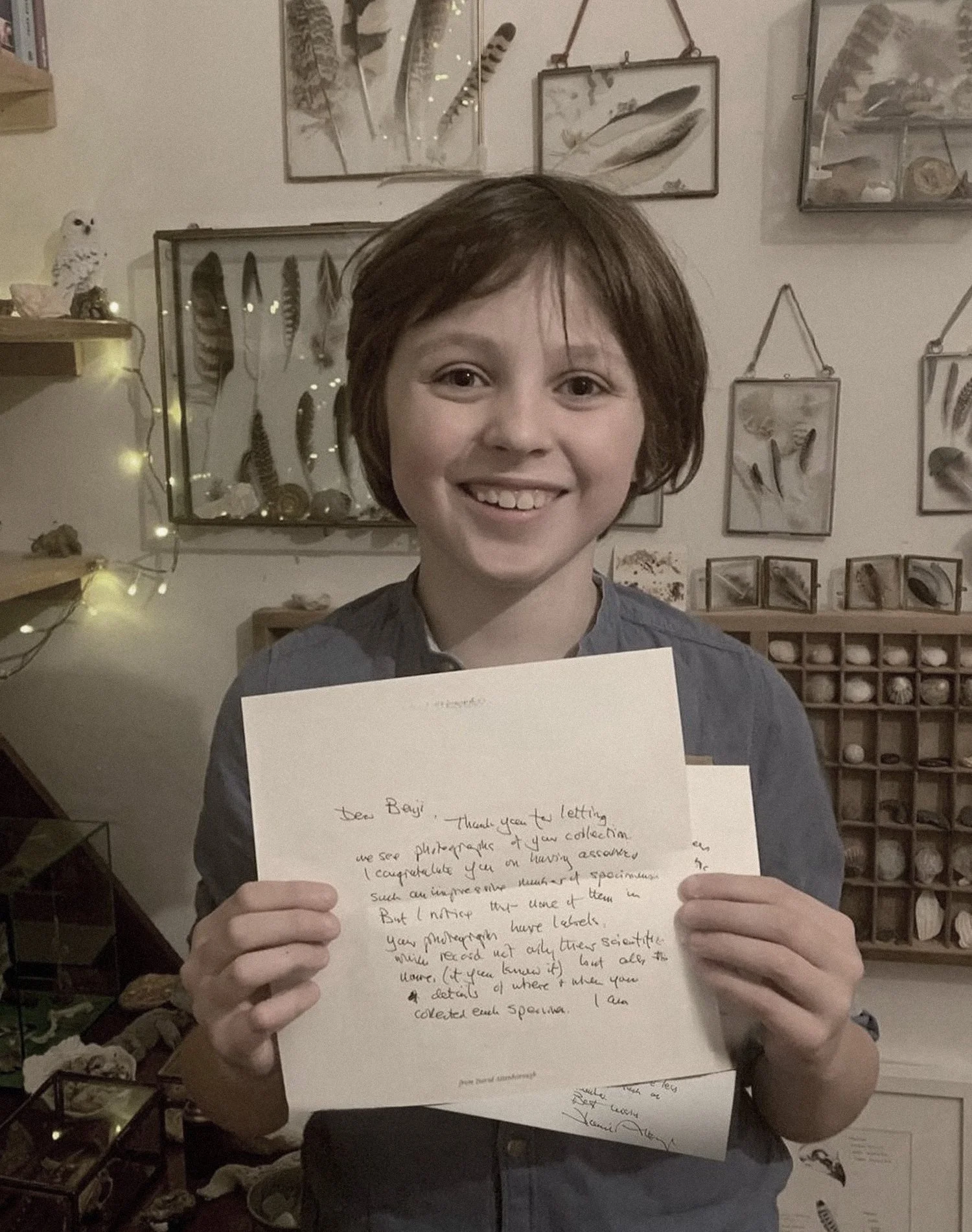Child holding letters with feather collection in background