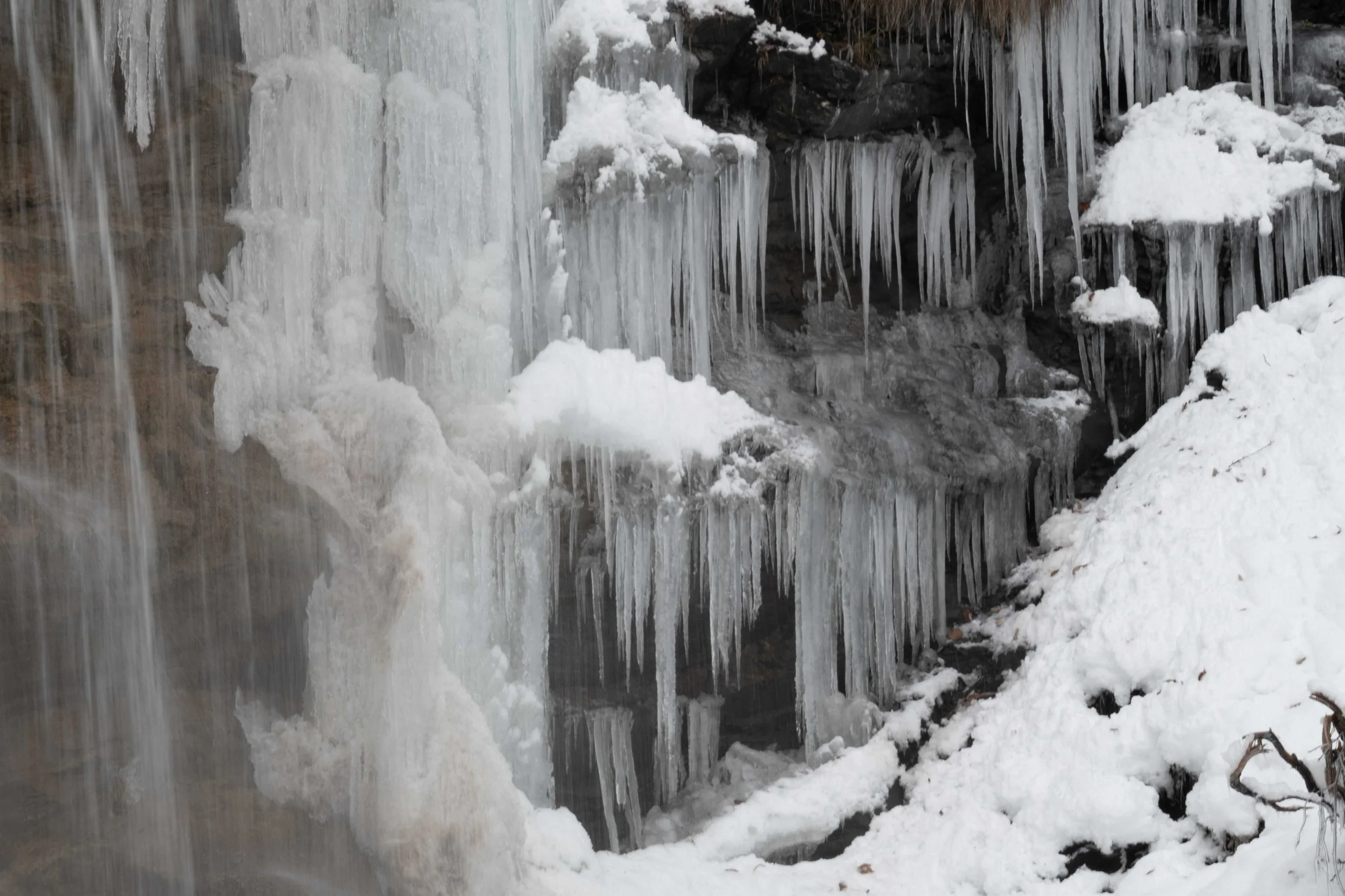 Formation de stalactites de glace sur des rochers enneigés.