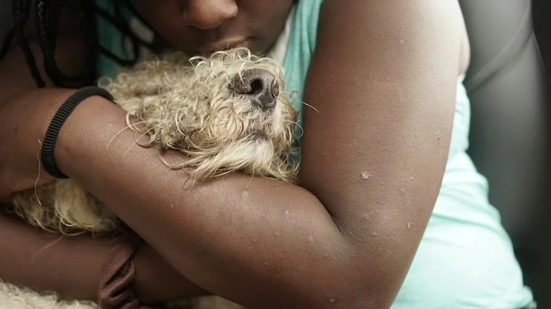 woman of color hugging bedraggled dog