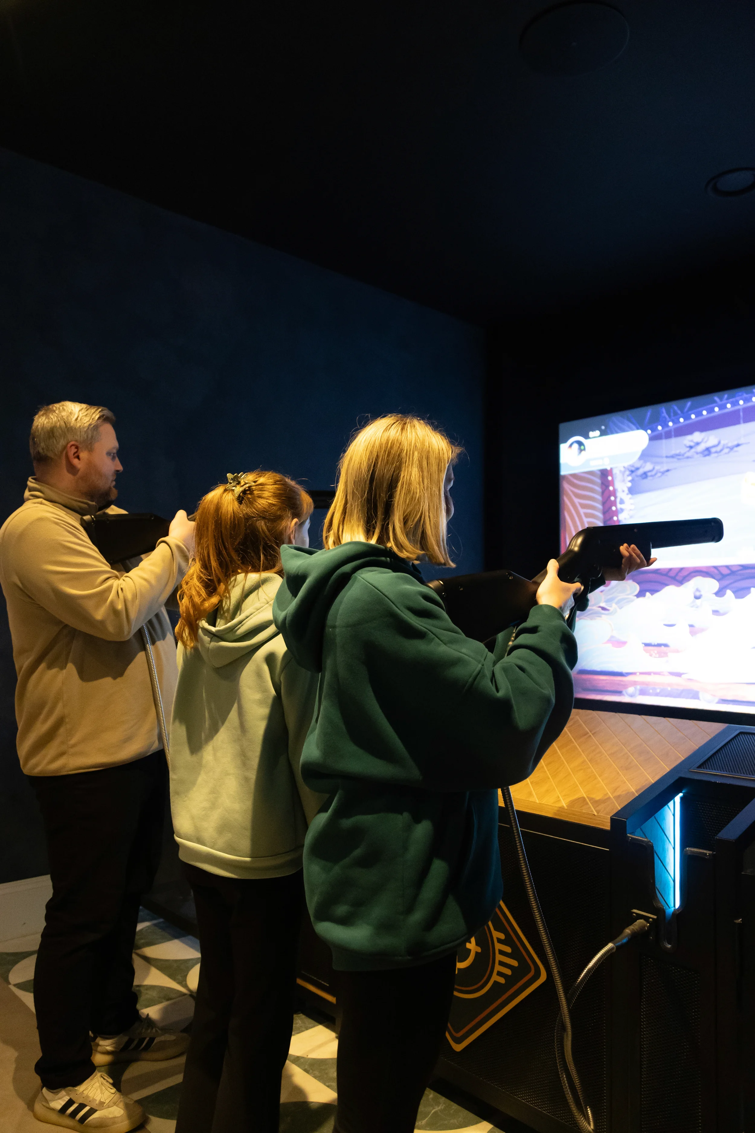 A family playing the Hotshots digital shooting gallery game by Game Volt