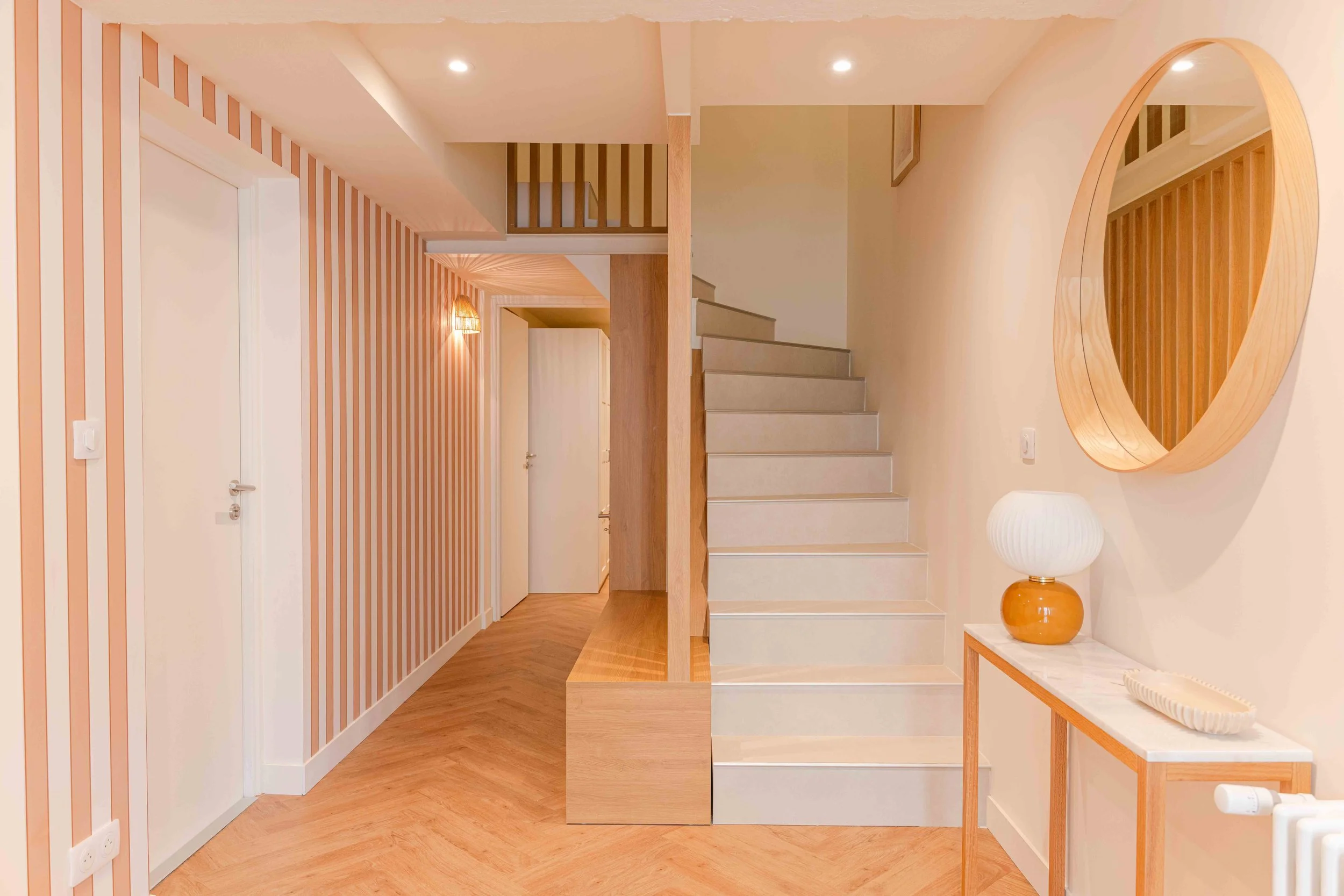 L’entrée fonctionnelle de la maison, distribue tous les espaces de ce niveau de la maison. Elle a été pensée comme un seuil chaleureux entre l’intimité du foyer et l’extérieur. Le meuble sur mesure en bois clair et le miroir circulaire définissent un