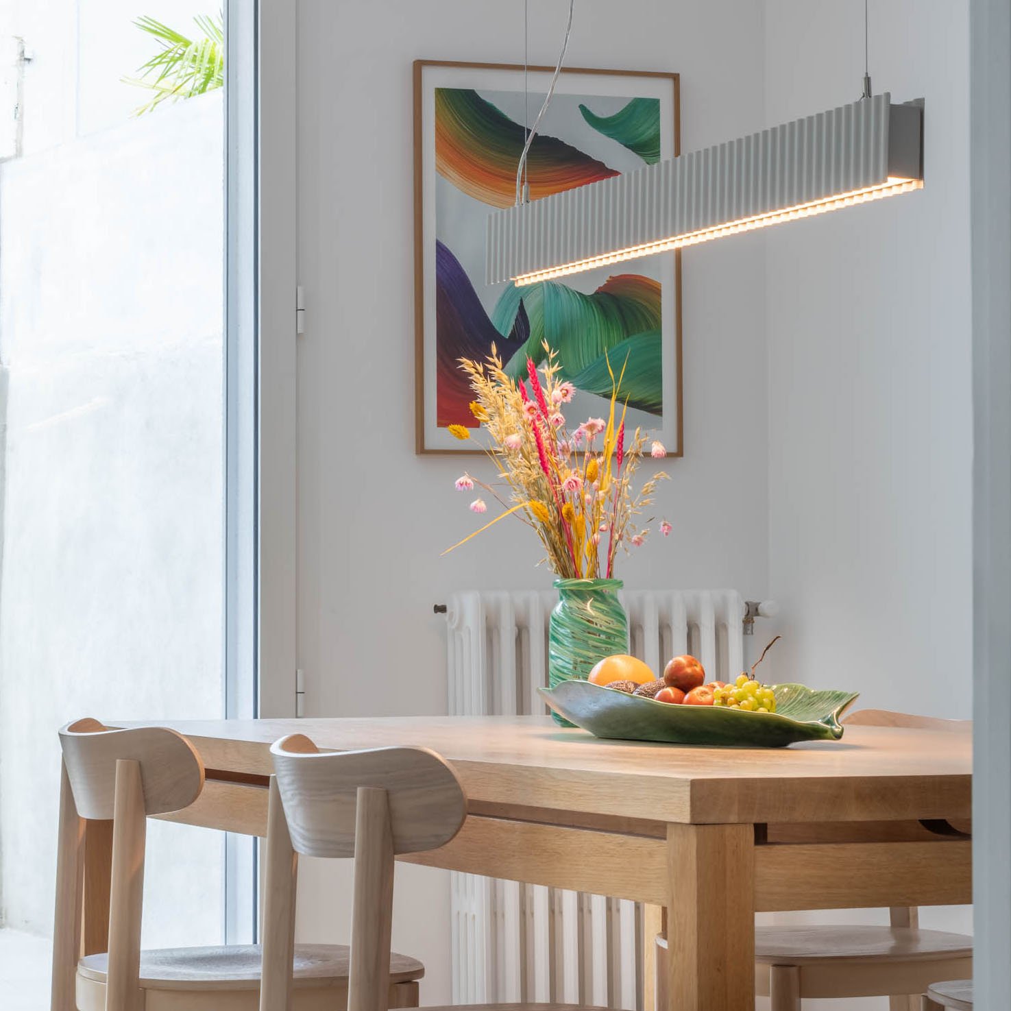 Rénovation de la salle à manger de la Maison Uchi à Toulouse, avec table en bois, suspension linéaire et aménagement intérieur lumineux par Atelier Kiso, architectes spécialisés en rénovation.