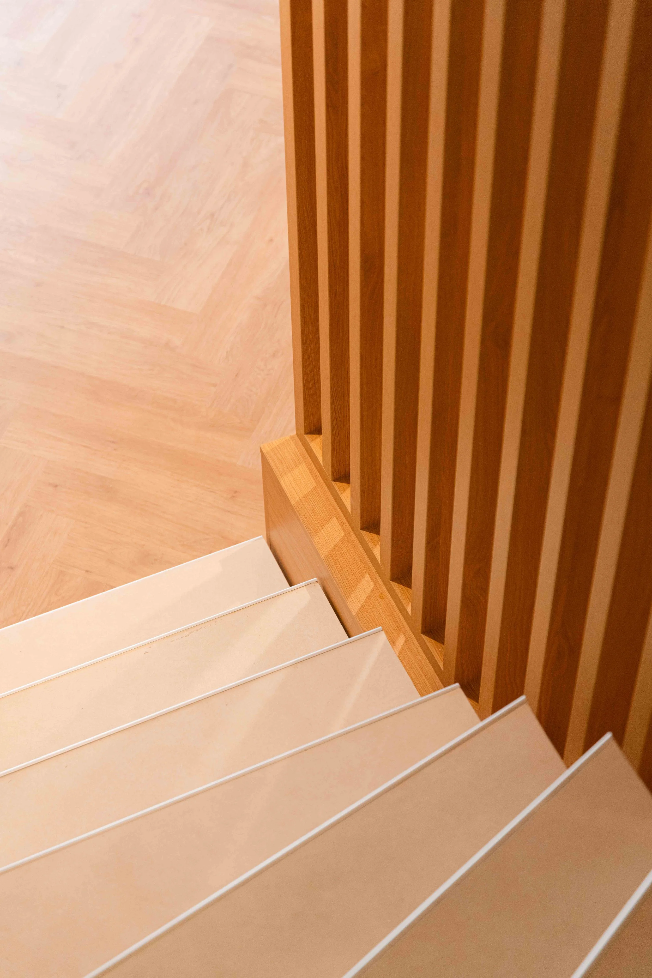 L'escalier a été réalisé en béton et carrelé. L'habillage latéral en bois dessine une trame régulière et verticale, comme une cloison diaphane : un exemple de transition fluide entre les étages. La rénovation du logement mêle fonctionnalité et esthét