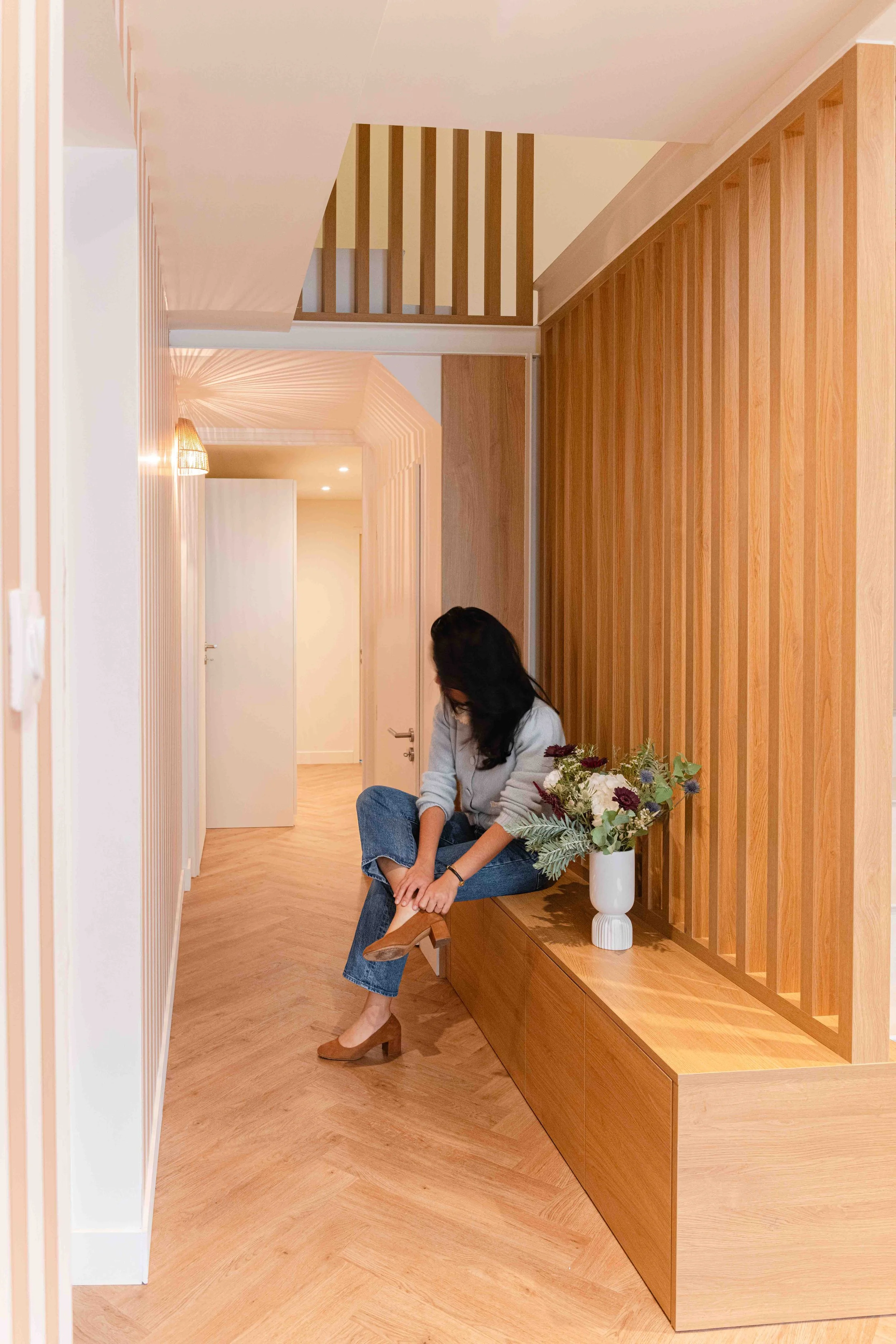 Détail du claustra en bois sur mesure conçu pour l’escalier en béton. Ce motif vertical rythme l’espace et prolonge l’ambiance douce de l’entrée. Atelier Kiso conçoit chaque élément dans une logique d’ensemble, typique de ses rénovations d’habitation