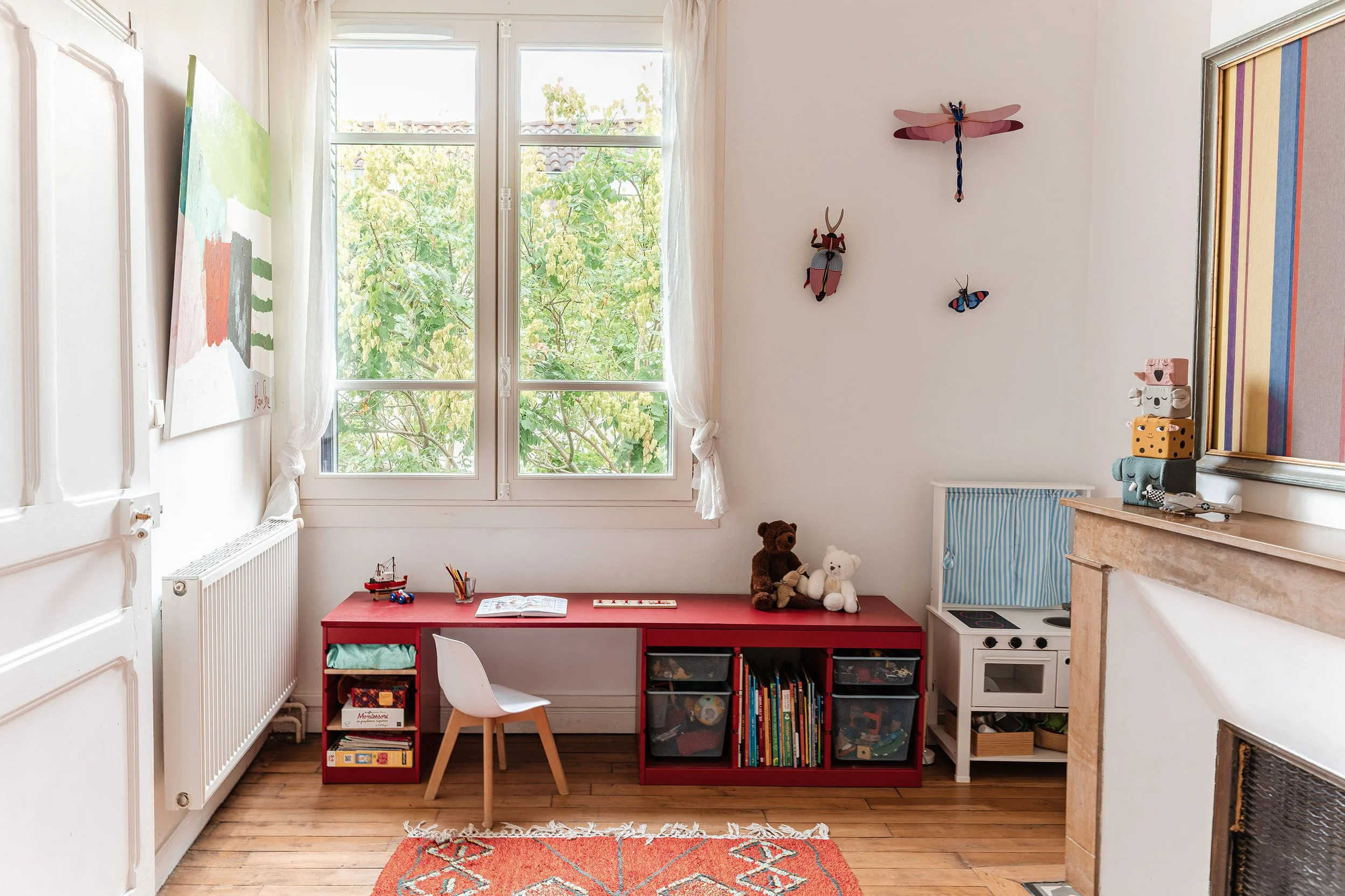 La chambre s'ouvre sur la canopée du patio. Un espace évolutif où lumière naturelle, rangements bas et mobilier favorisent l'autonomie des enfants.