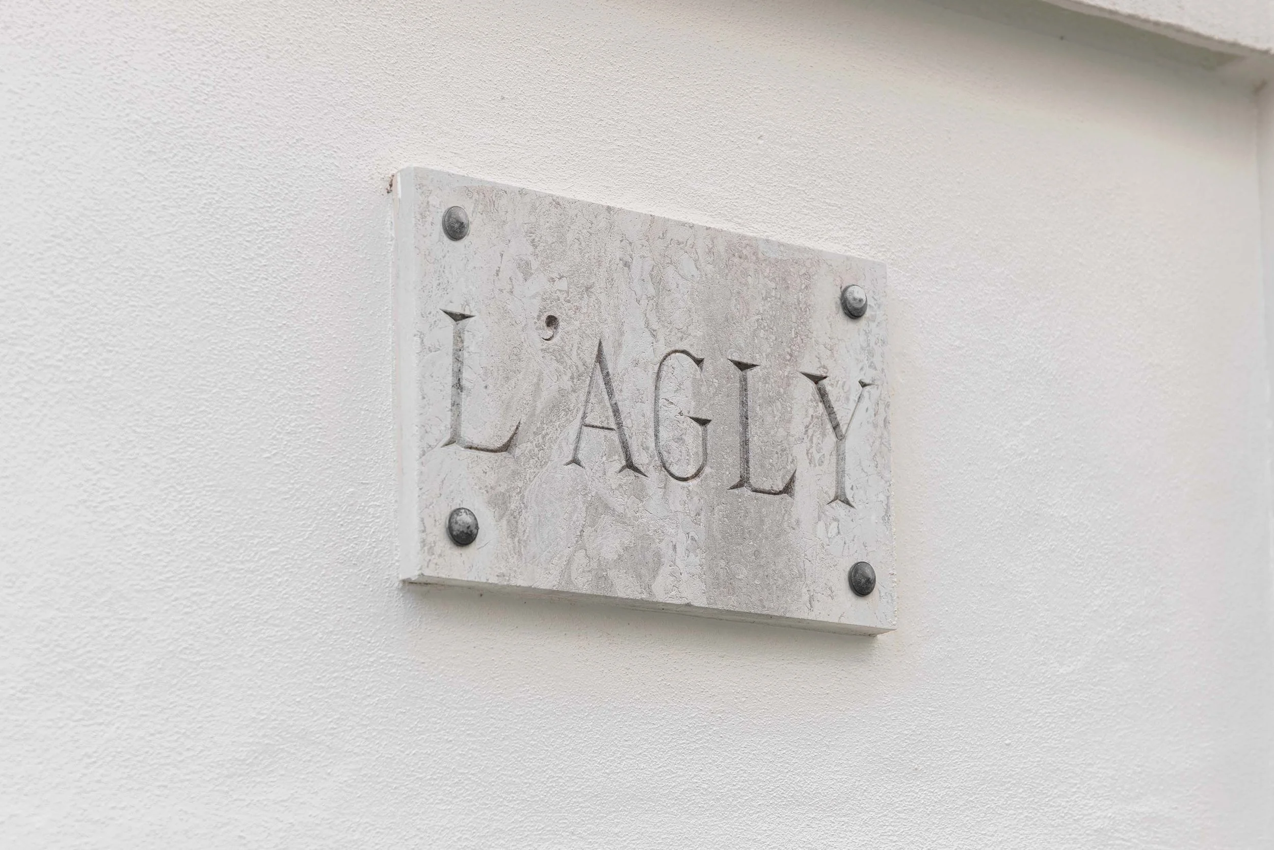 Plaque en marbre du nom de la maison : L'AGLY (Aglí en catalan, Aglin en occitan) fleuve côtier du sud de la France, qui coule en Roussillon, dans la nouvelle région Occitanie.
