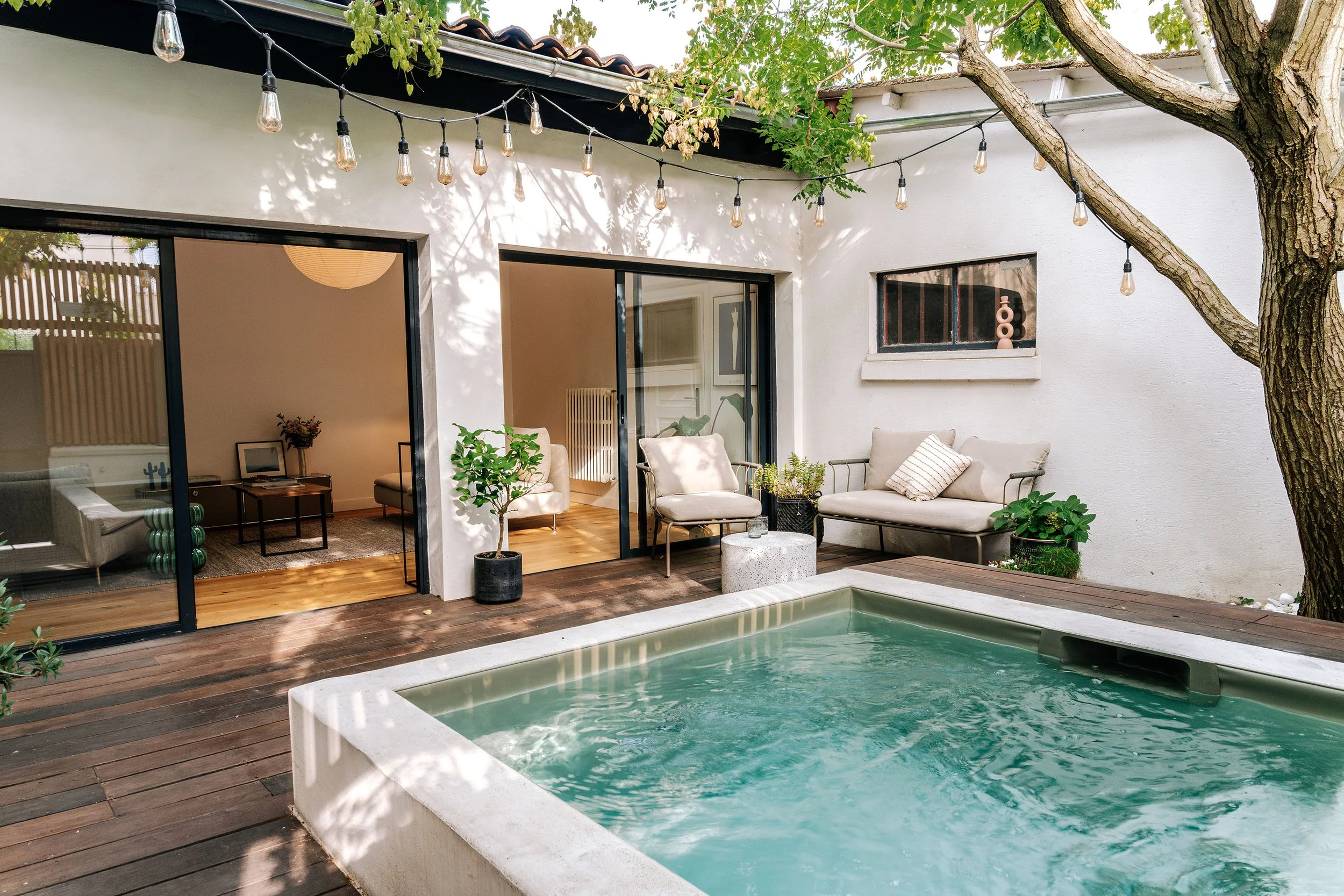 Le patio devient une pièce à vivre à ciel ouvert. L'arbre existant, le bassin et les grandes ouvertures composent un espace de fraîcheur au cœur de la maison.