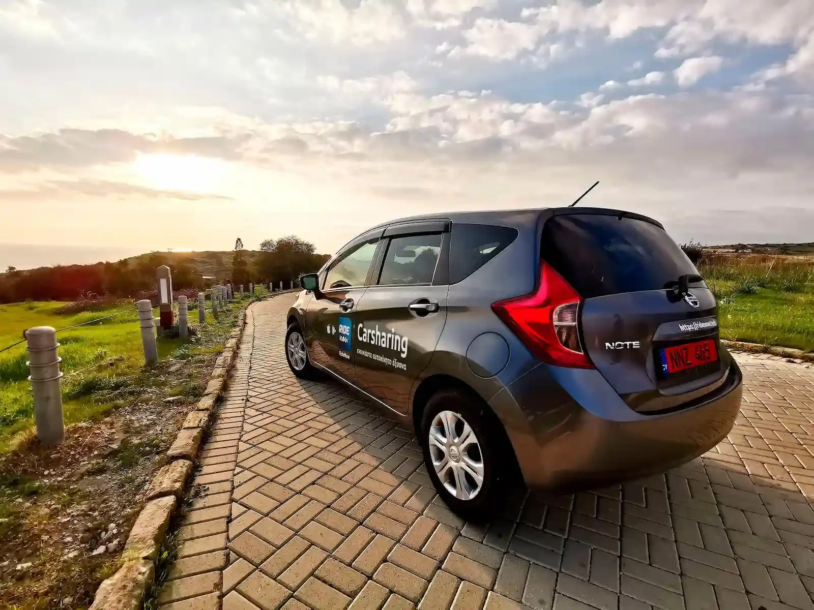 RideNow carsharing car parked on a coastal path in Cyprus at sunset, ready for a package or InterCity trip