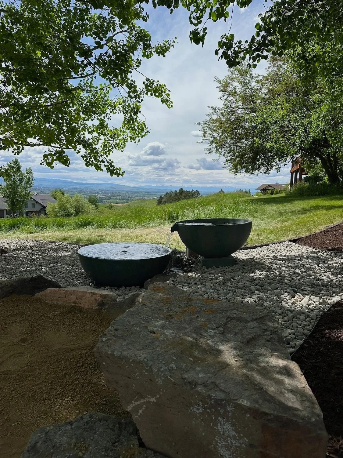 A pond less water feature that displays a spillway bowl, pouring into another bowl for a calming landscape addition.