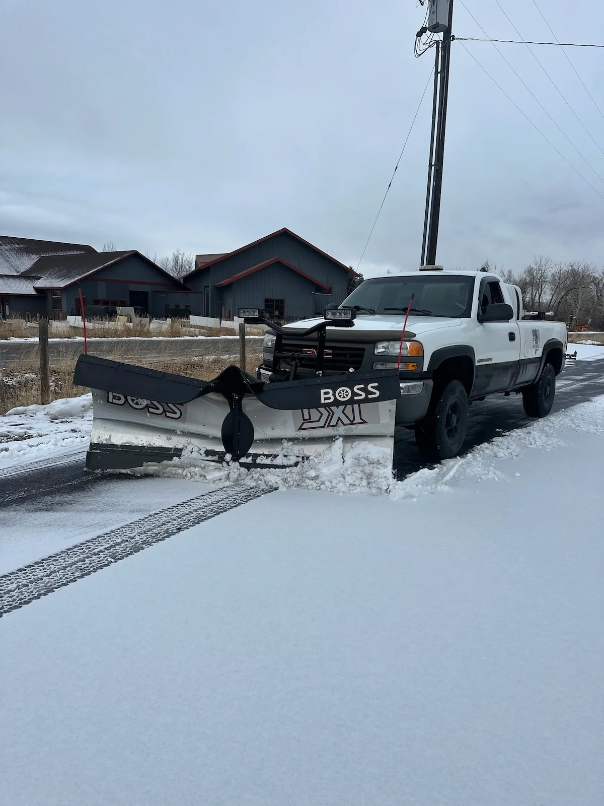 White Pines snow plow truck clearing a commercial parking lot in Four Corners.