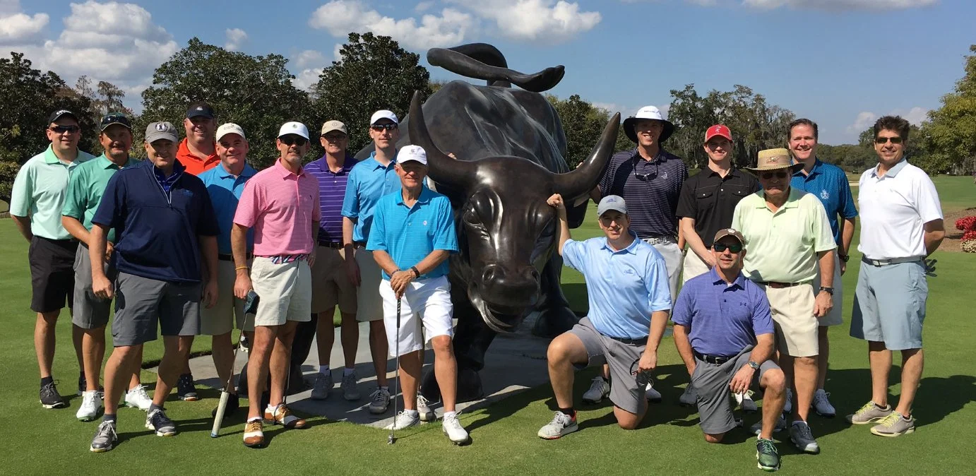 Donor event guests posing by iconic bull statue at golf course – fun group photo during a memorable fundraising experience.