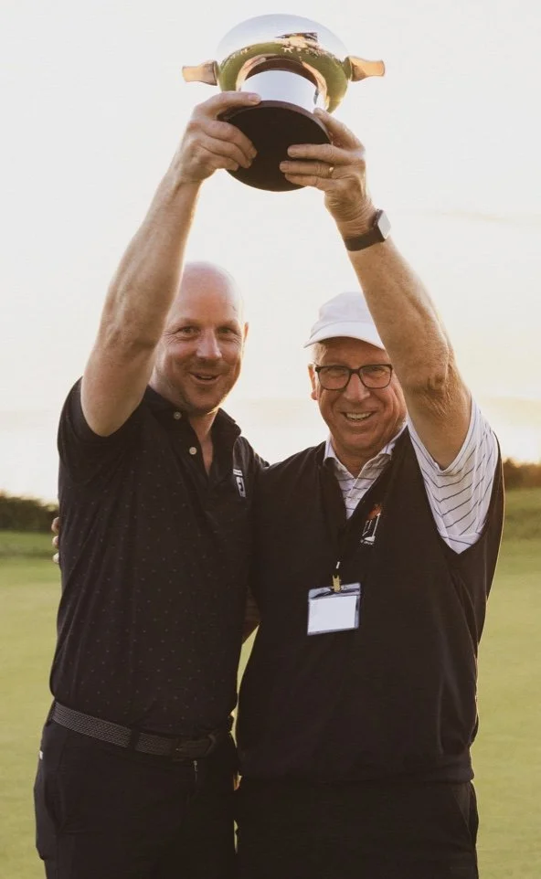 Winners celebrating with trophy at sunset during a donor golf tournament – joyful recognition after a successful day on the course.