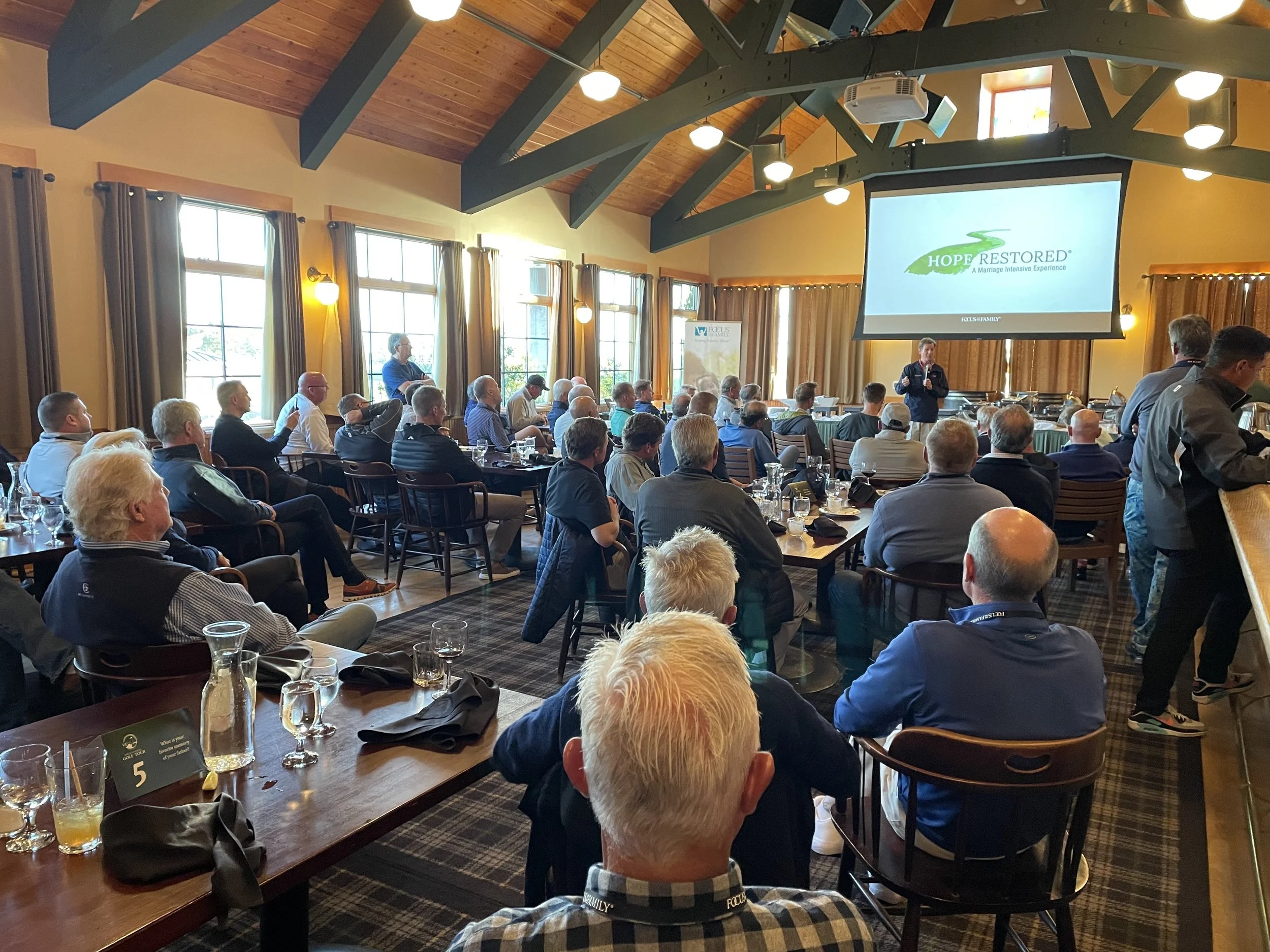 Attendees listening to a speaker at ‘Hope Restored’ donor event – impactful indoor session complementing the charitable golf experience.
