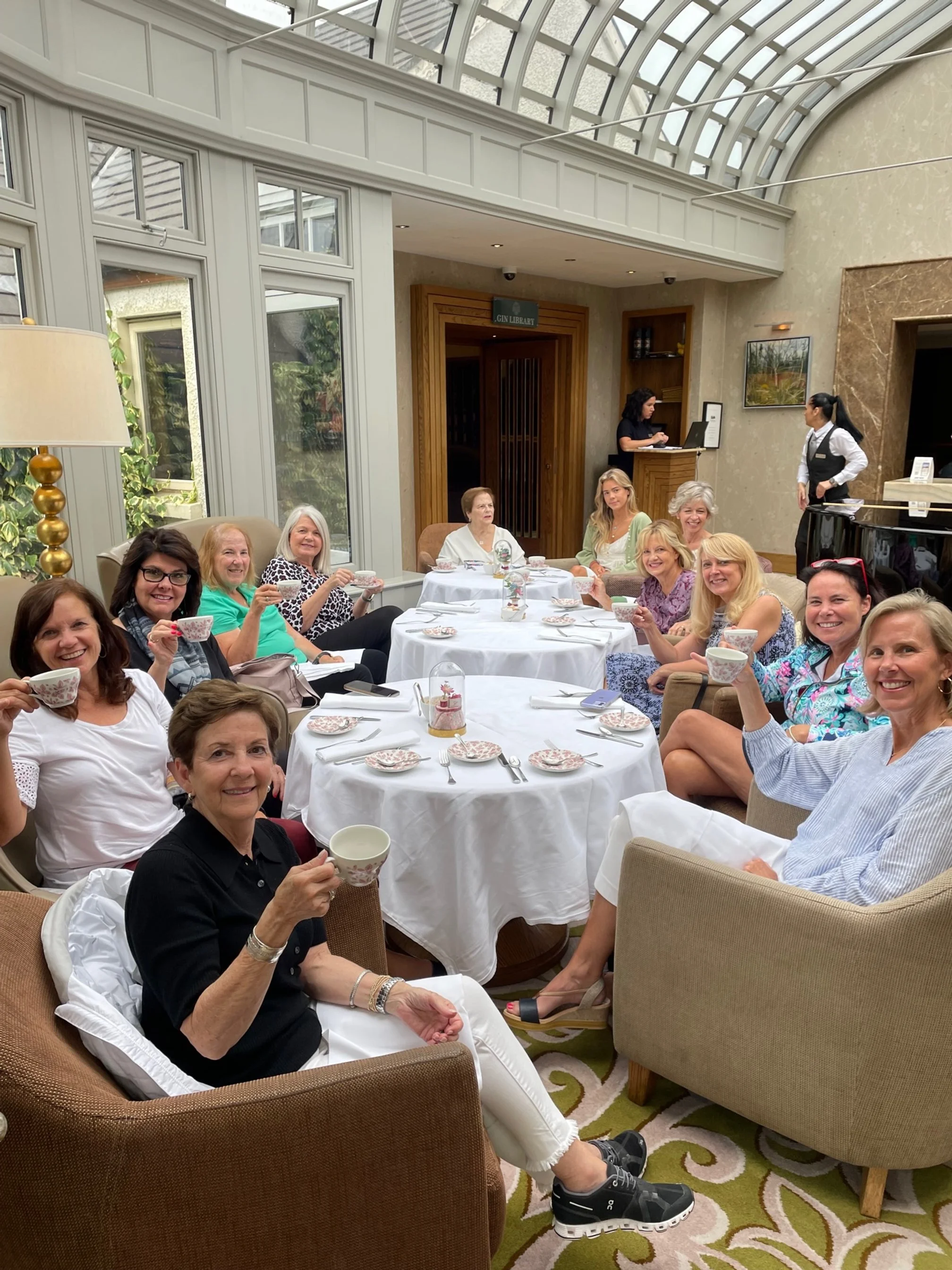 Guests enjoying afternoon tea during a donor golf event – off-course gathering in an elegant indoor lounge with white table settings.