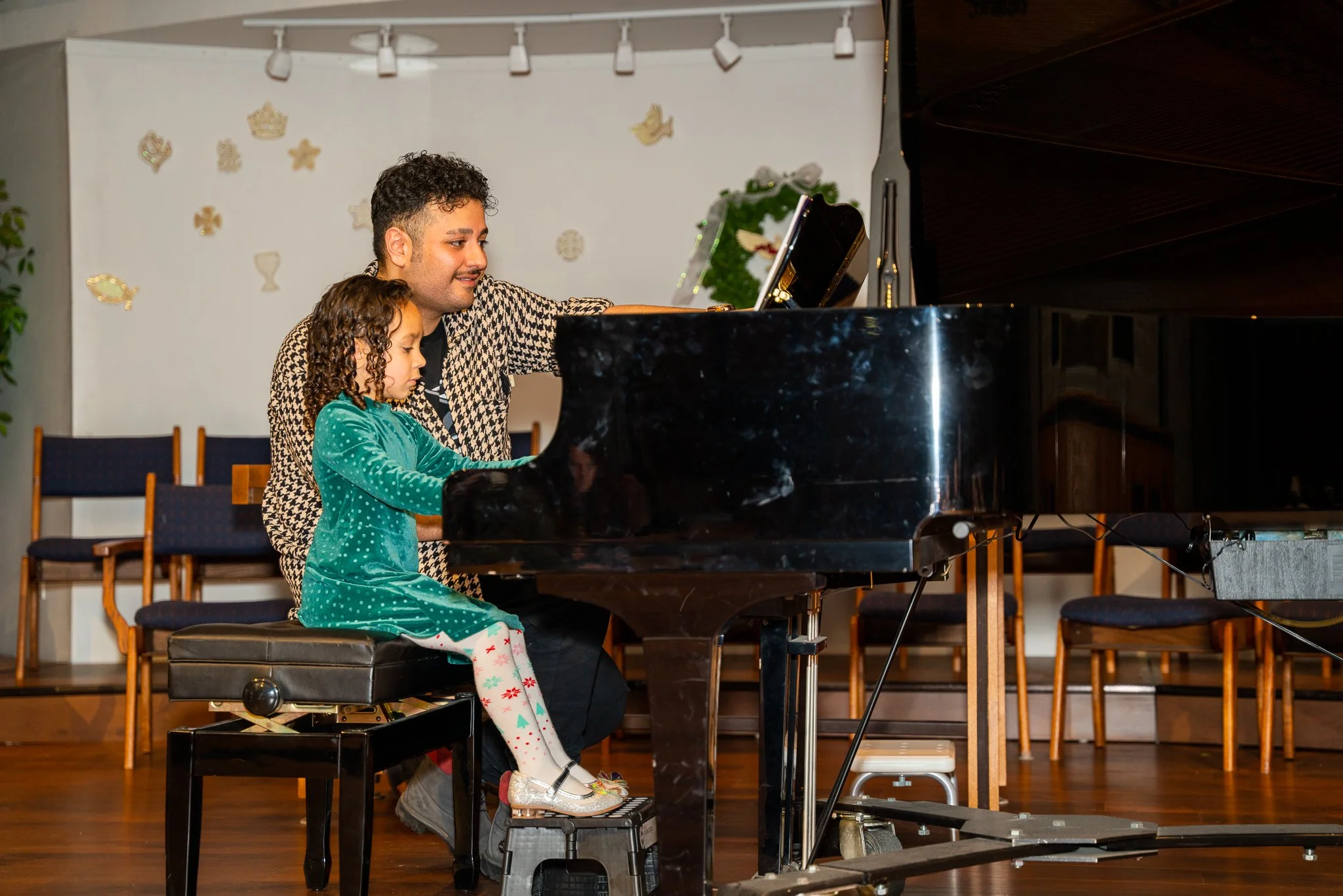 Soroush performing at the 2022 piano recital with his 3.5-year-old student Layla as they smile together on stage