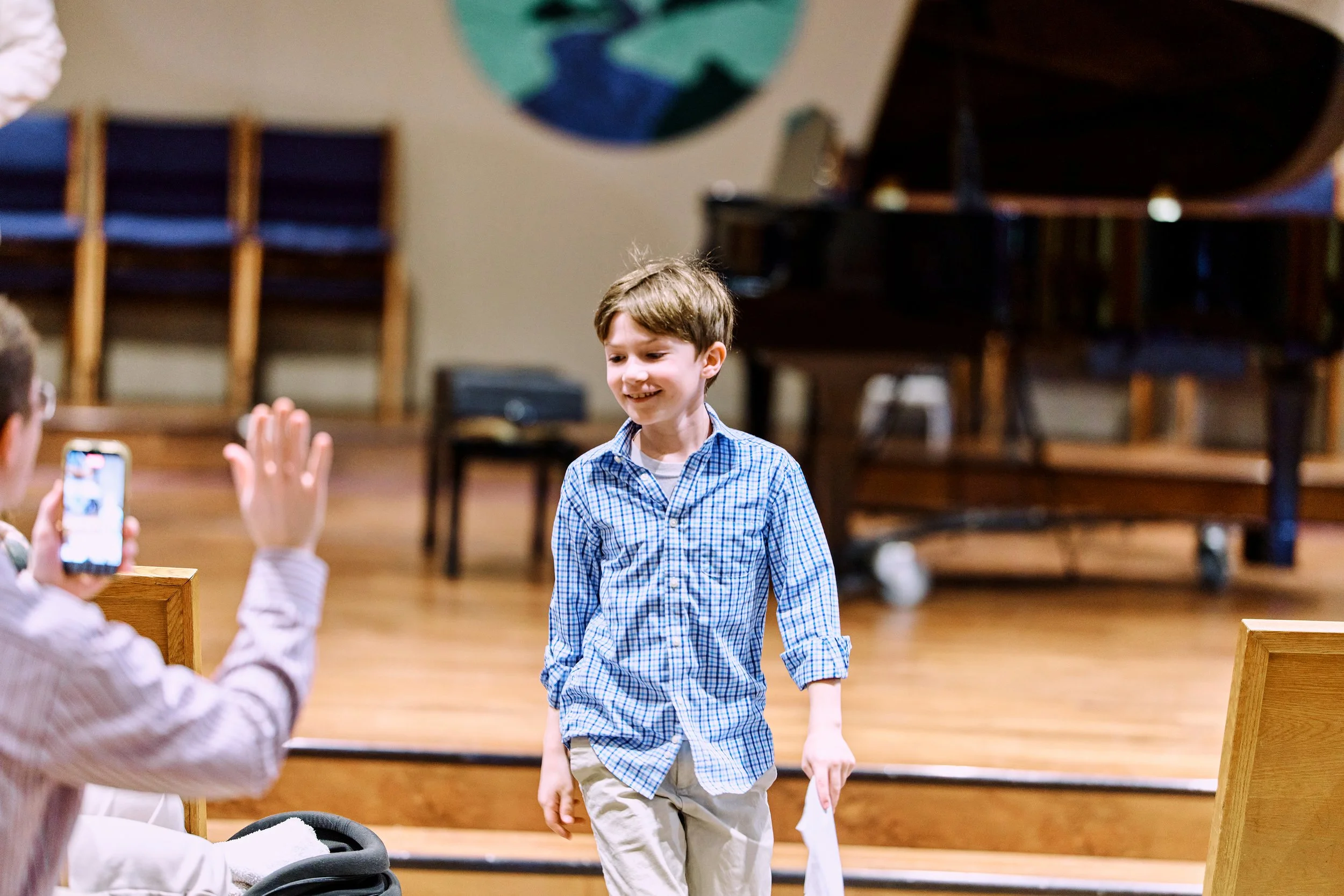 van smiling as he walks toward his dad after performing at a Naji Piano School recital.