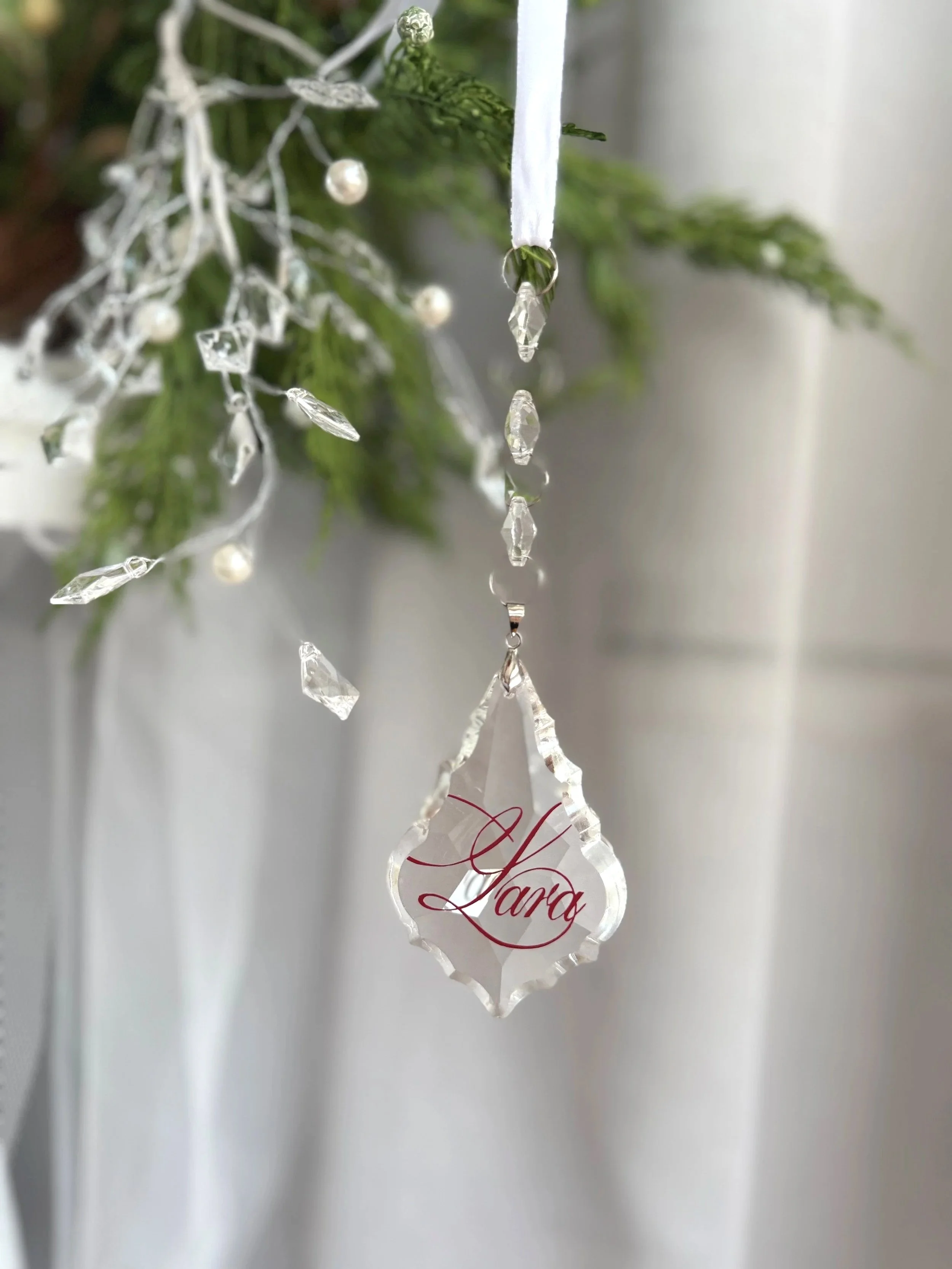 Personalised crystal Christmas ornament with custom engraving hanging on a decorated tree
