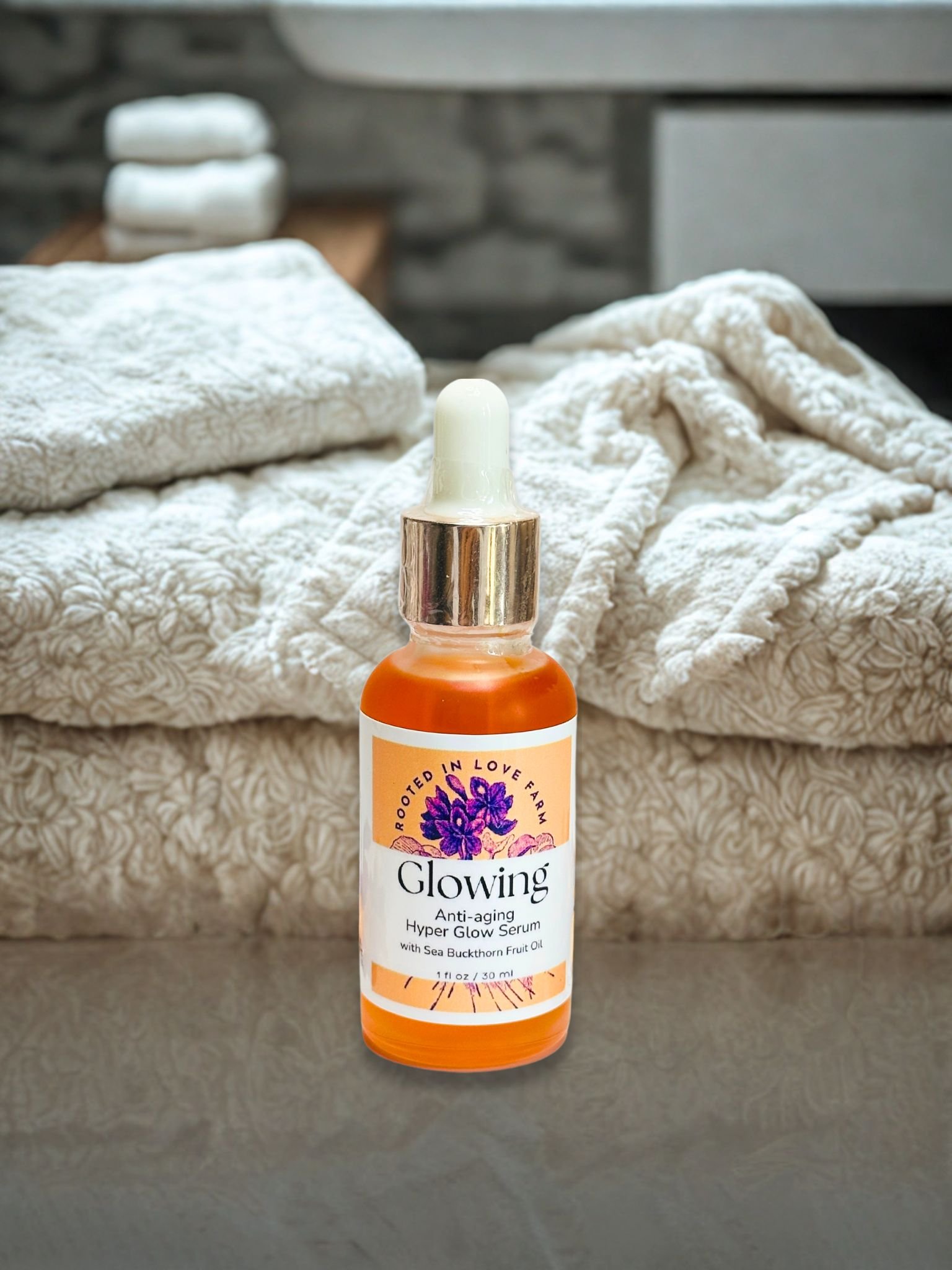 Glowing anti-aging Serum with soft towels in background Rooted in Love Farm.jpg