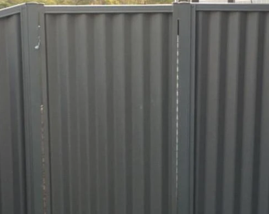 A metal fence with vertical corrugated panels.