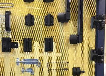 Display of various black gun safes and storage cases mounted on a yellow pegboard.