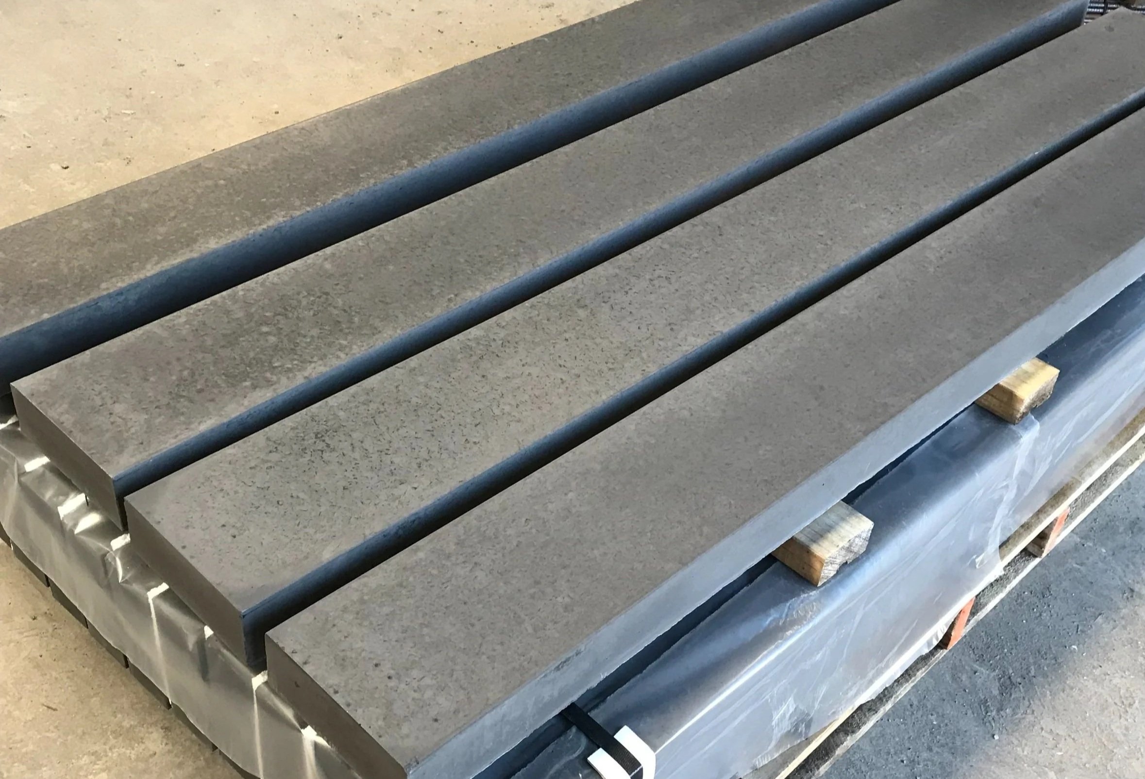 Several dark grey concrete sleepers on a wooden pallet.