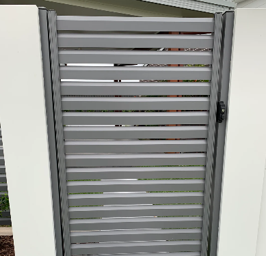 Grey horizontal slatted gate or fence with a black latch on the right side, between two white posts.