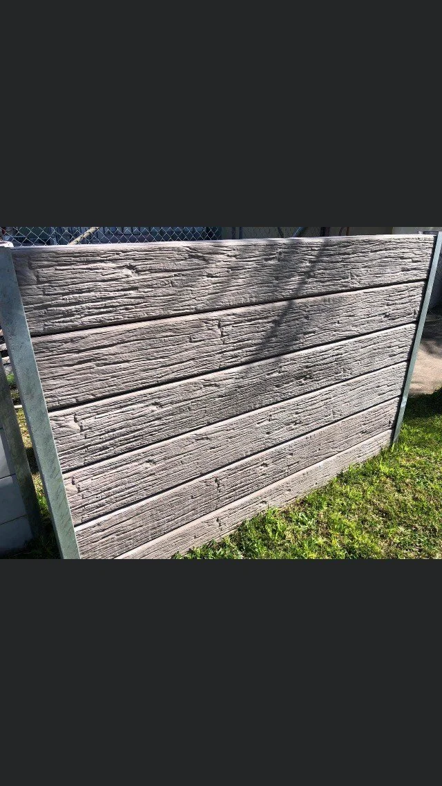Timber grain concrete sleepers, supported by metal framing, situated outdoors on grass.