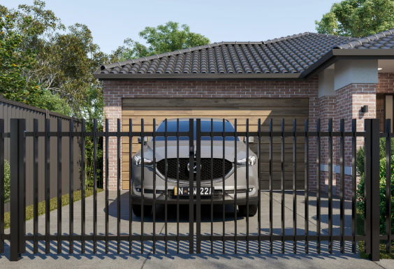 Silver car parked in front of a brick garage, behind a black metal fence, in a suburban yard.