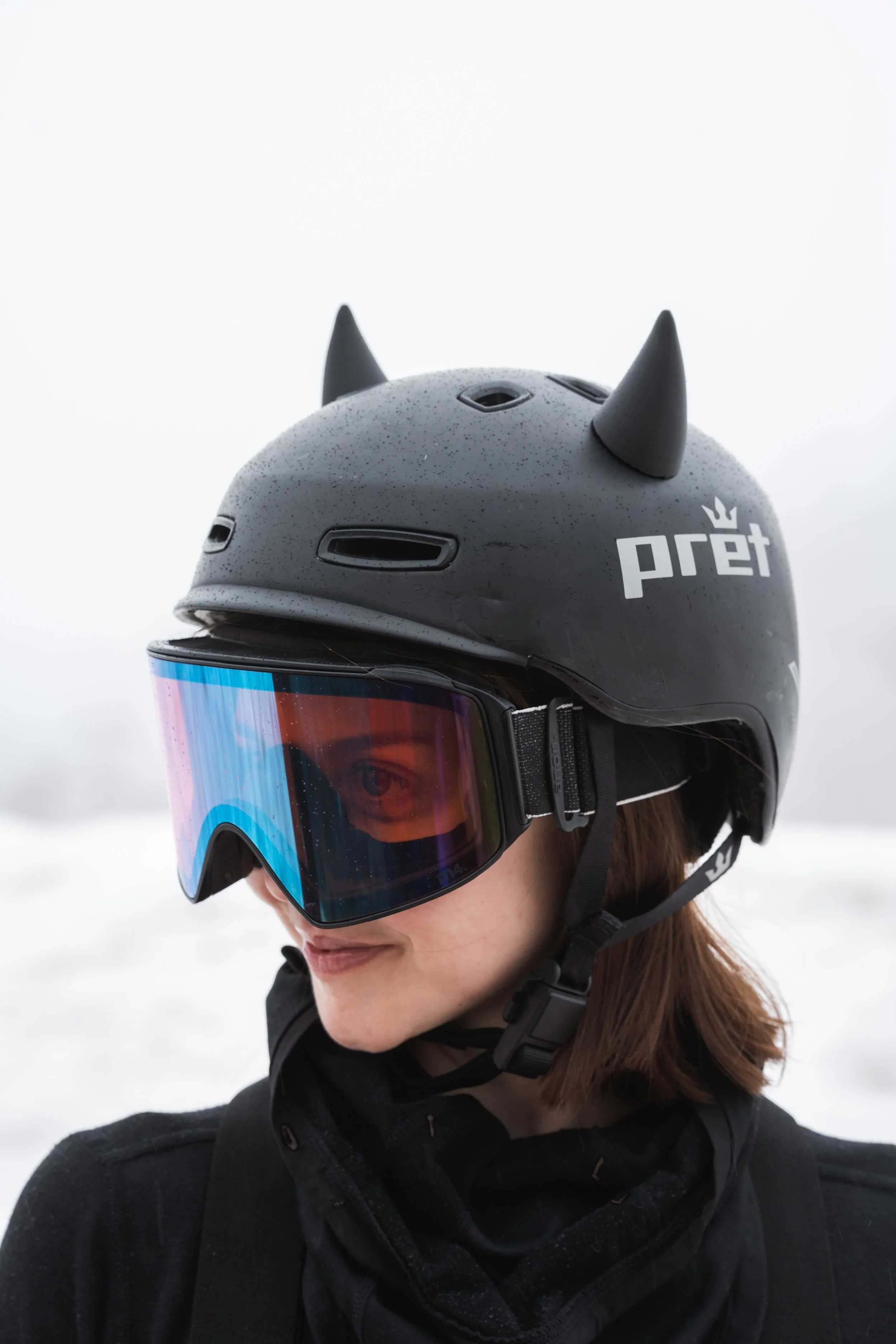 Black snowboard helmet with 3D printed horn ears on a snowy mountain