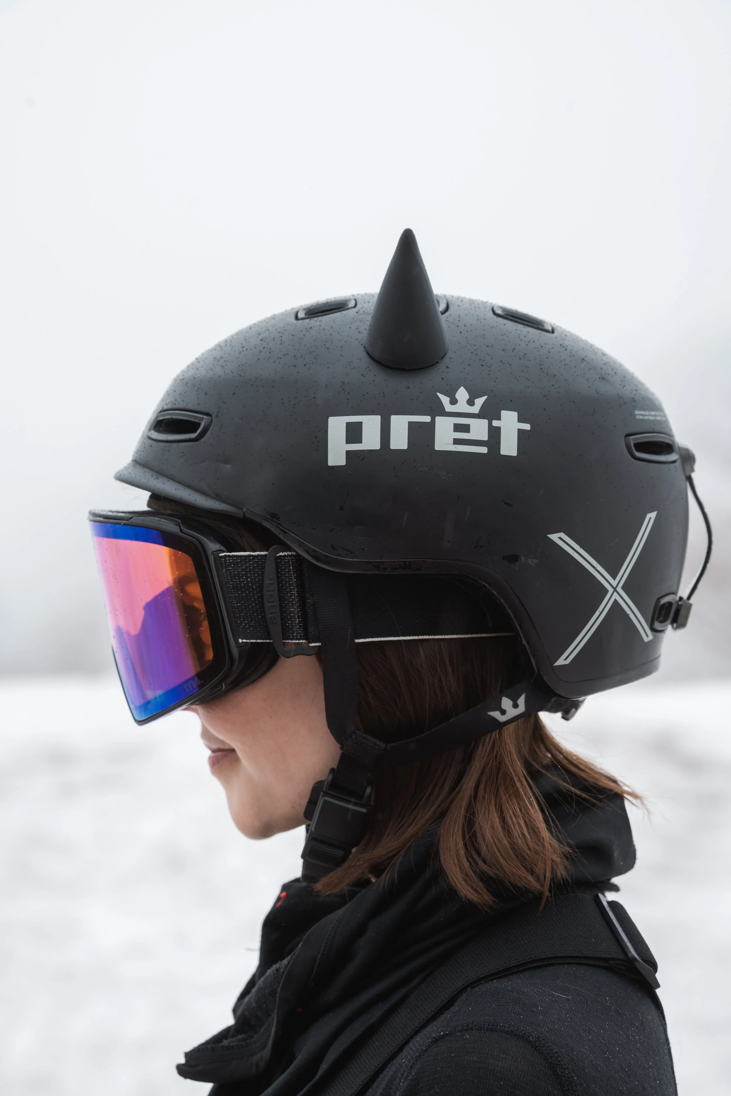 Black snowboard helmet with 3D printed horn ears on a snowy mountain