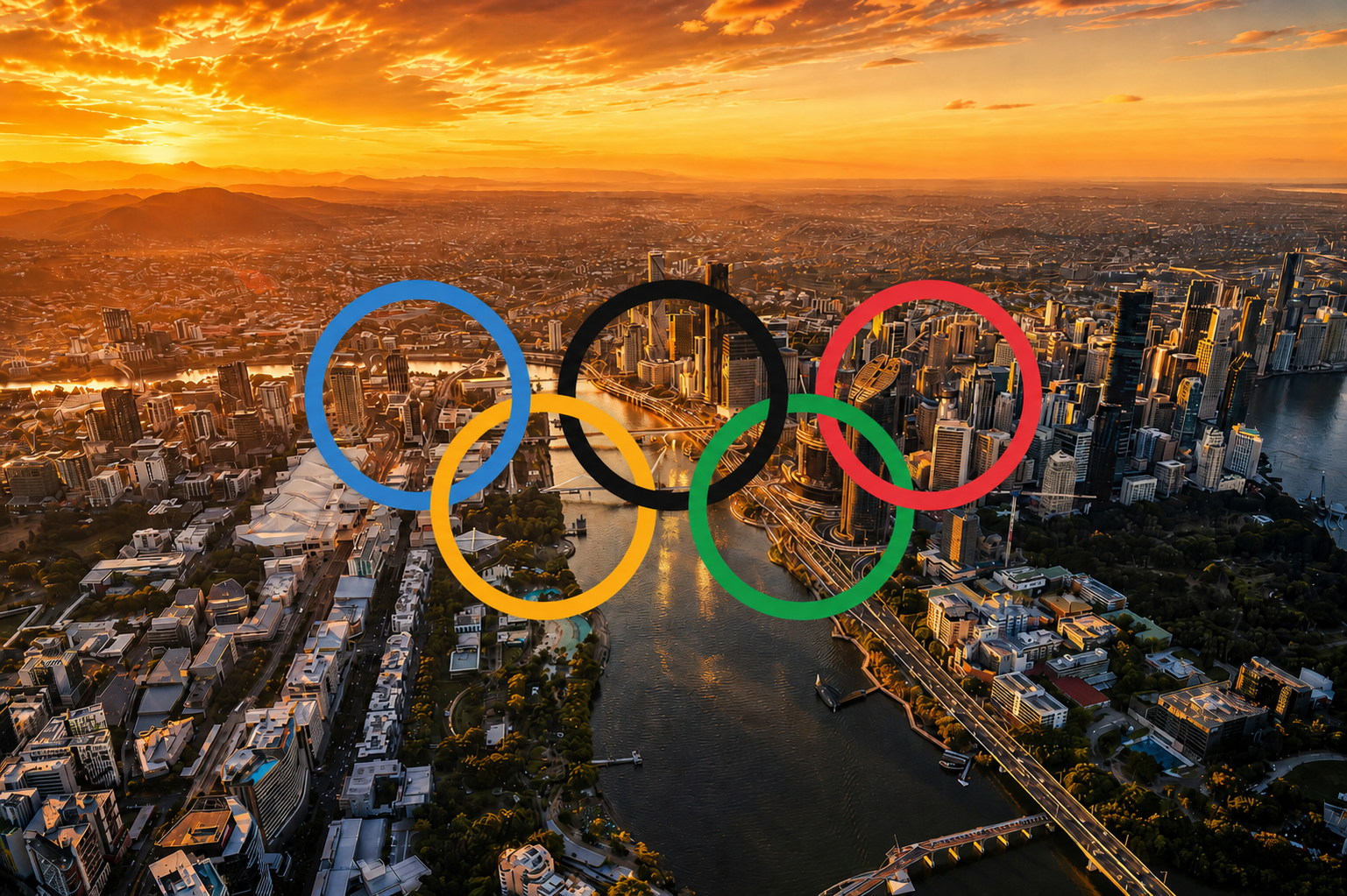 Aerial view of a city at sunset with Olympic rings overlayed in the sky.