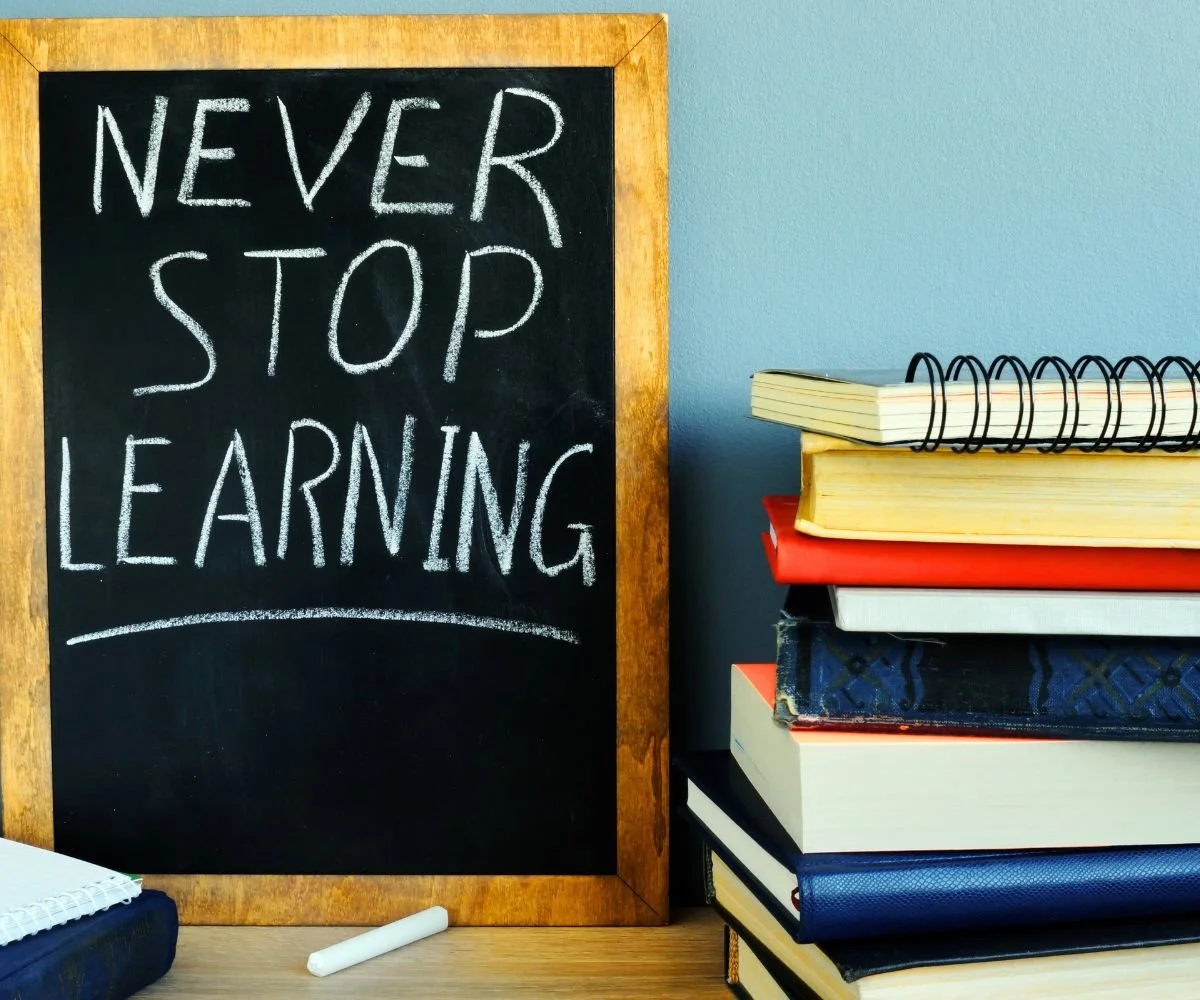 stay resilient: a small chalkboard with 'never stop learning' written on it next to a stack of books