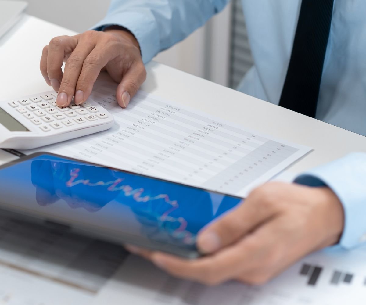 The New Government Budget - close up of a male business man using a calculator with spreadsheets and a tablet