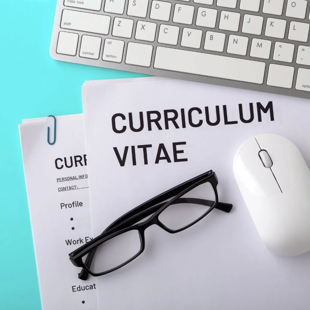 A CV and glasses on a blue desk with a computer keyboard - ready for Mortgage Advisor recruitment