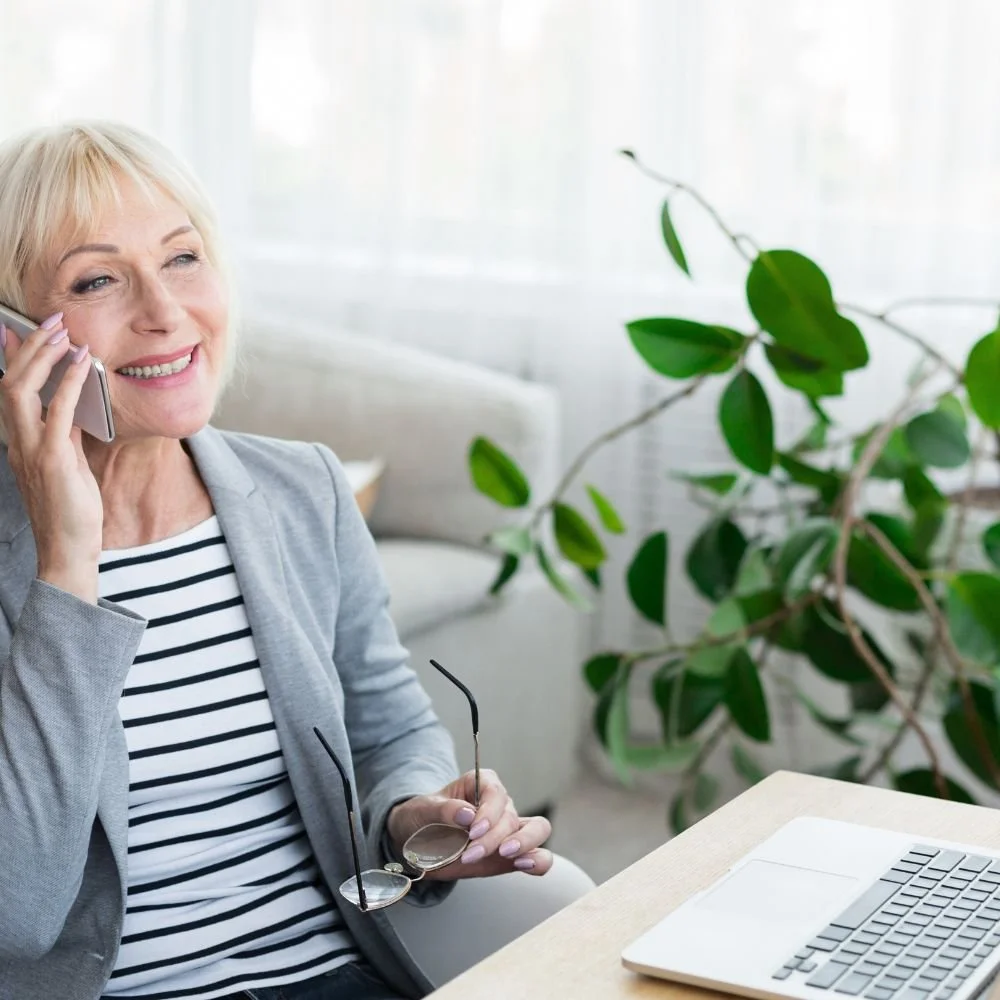 Blonde Business lady talking on her mobile at her desk for improve your recruitment process blog