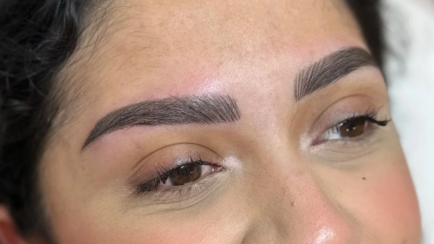 Close-up of a woman's face showing well-groomed eyebrows, light makeup, and brown eyes.