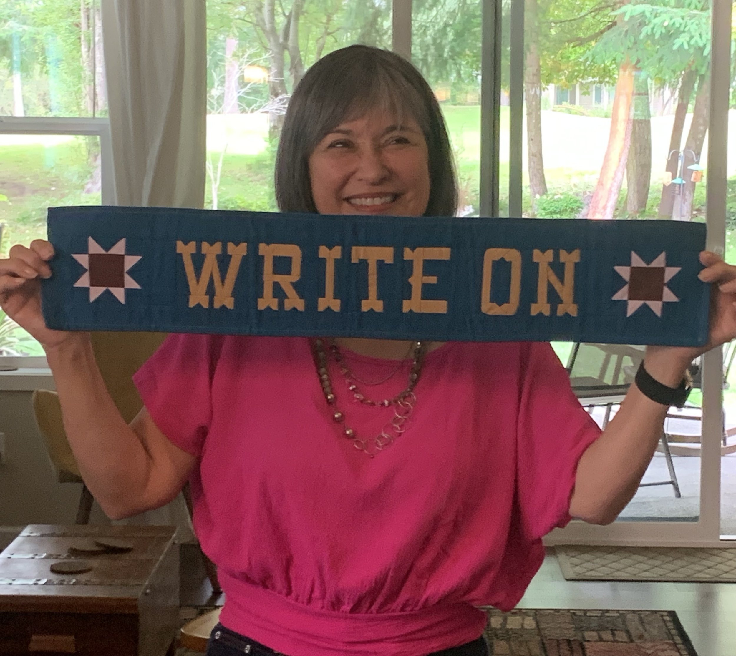 Maria Lynn Barrs, award winning author of the Vicky Robeson mystery series, shows off her quilted banner handcrafted by her daughter.