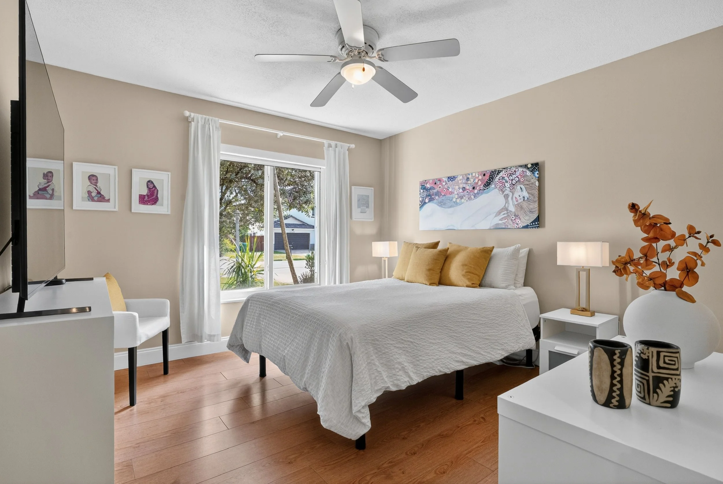 Bright secondary bedroom with hardwood floors, soft neutral décor, and natural light creating a calm, comfortable atmosphere. The simple layout and warm tones enhance the room’s relaxing feel.