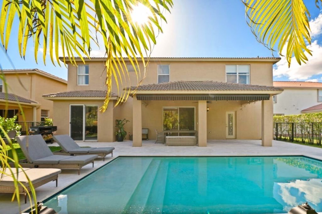Backyard of a family home in The Isles, Weston FL, featuring a private pool and covered patio.