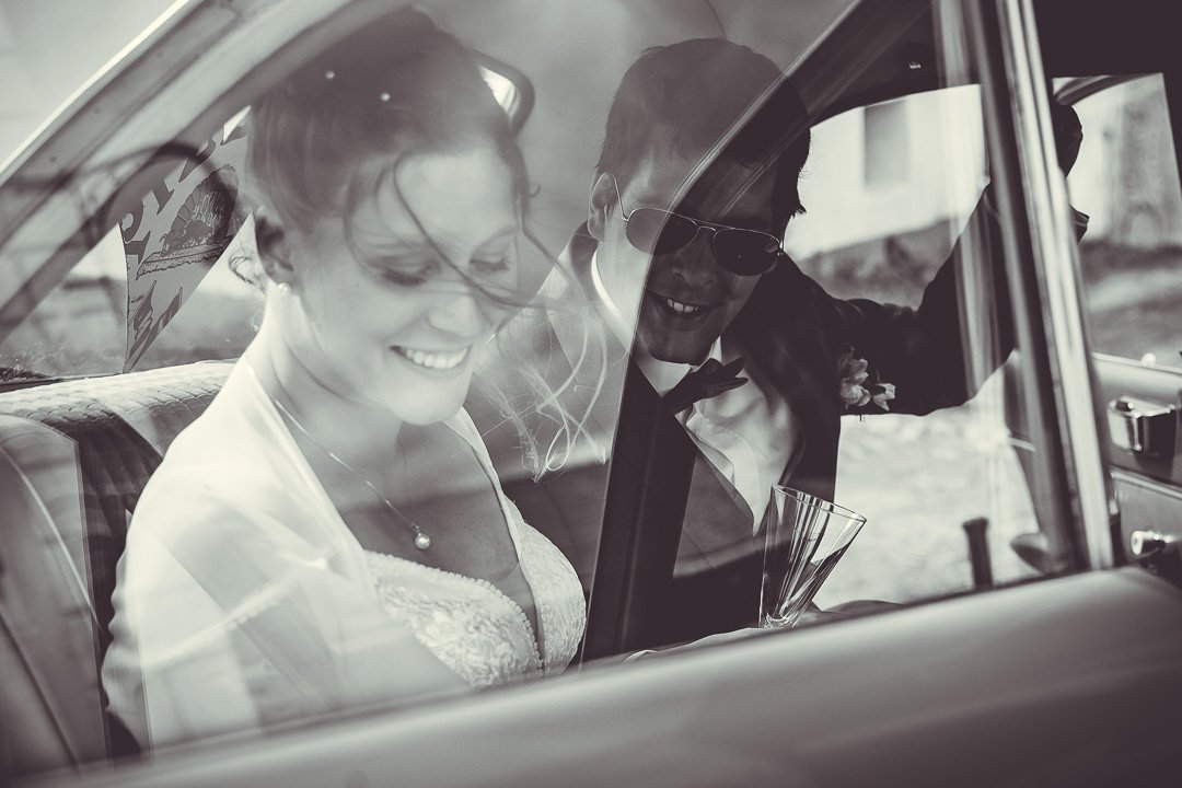 Paar in Hochzeitskleidung im Auto, schwarz-weiß Foto