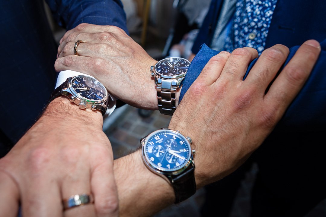 Drei Hände mit Armbanduhren, die elegante, blaue Zifferblätter zeigen.