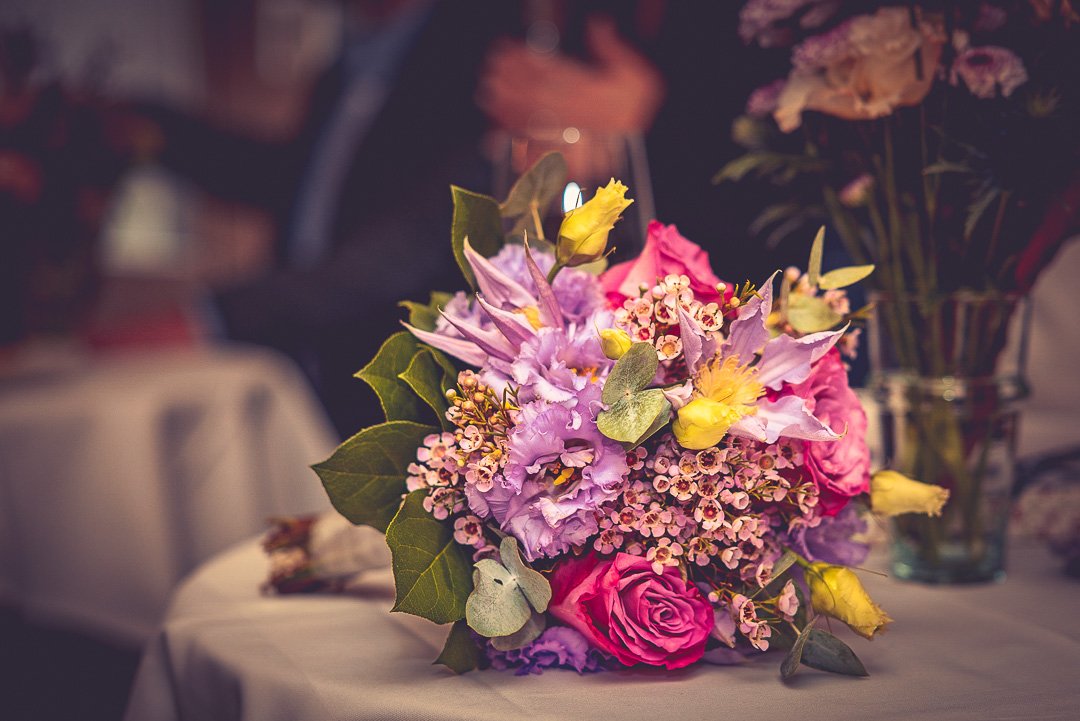 Ein Blumenstrauß mit lila, pinken und gelben Blüten auf einem Tisch.