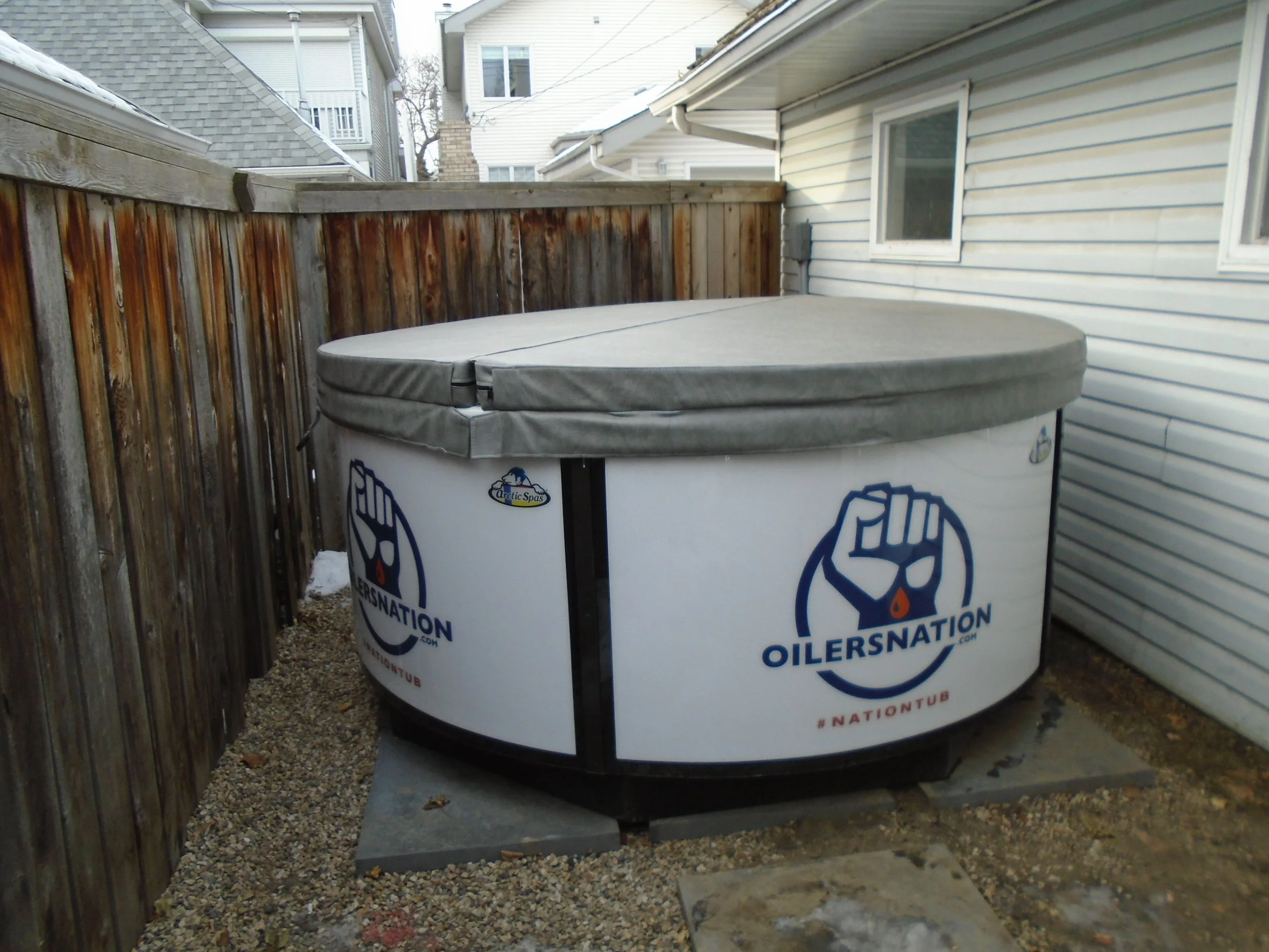 Hot tub with lid located on paving blocks.