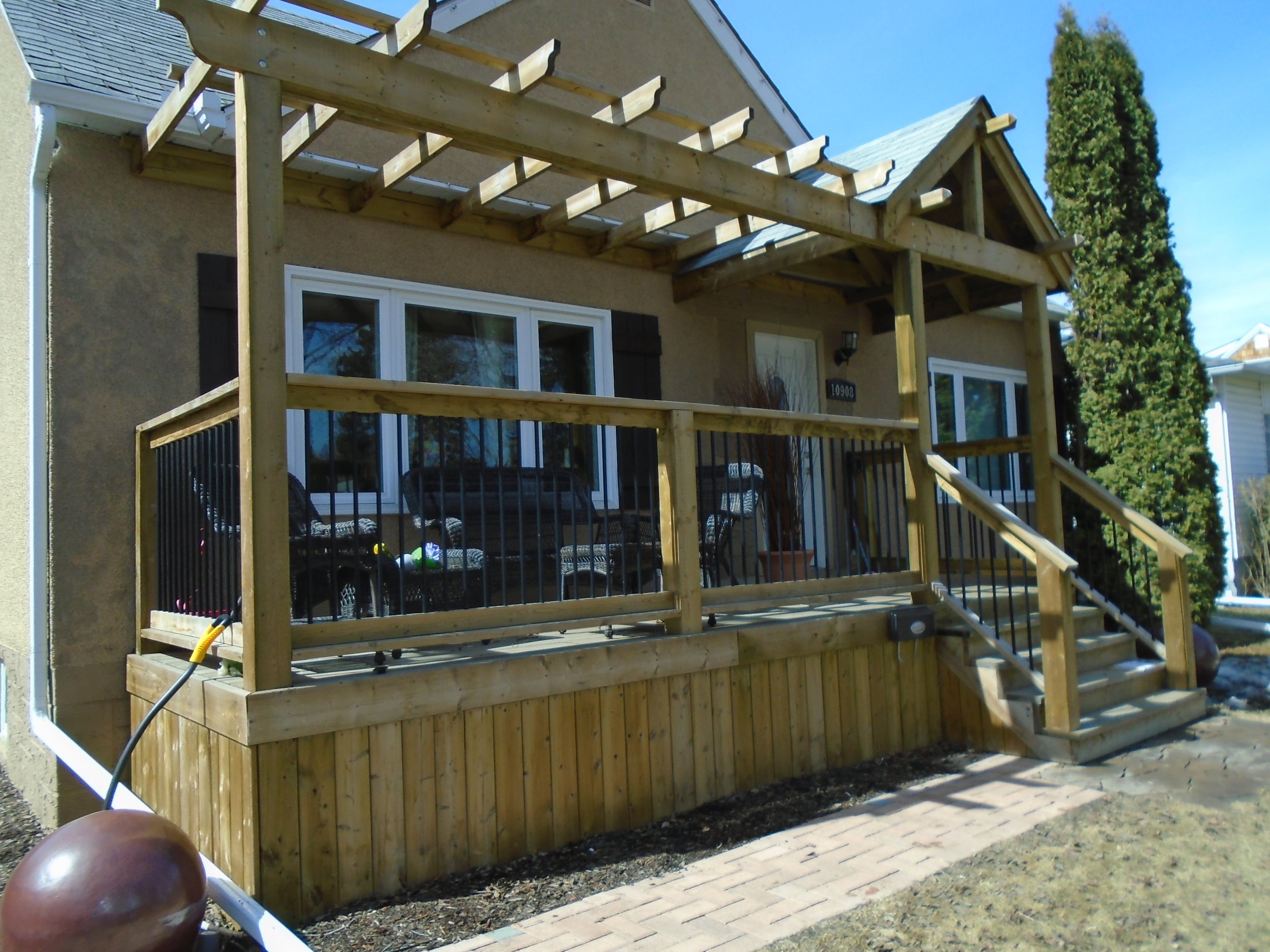Front wood deck with pergola and partial roof cover, located in a mature neighbourhood.