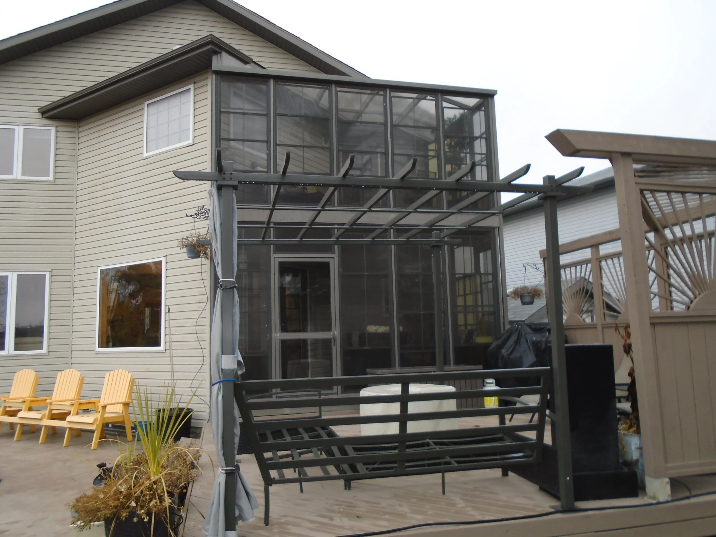 Two-storey screenroom attached to the house with outdoor wood pergola on patio.